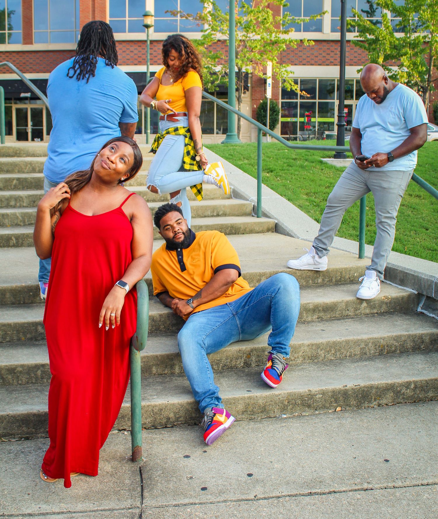 A group strikes dramatic poses on concrete steps outside a modern building.