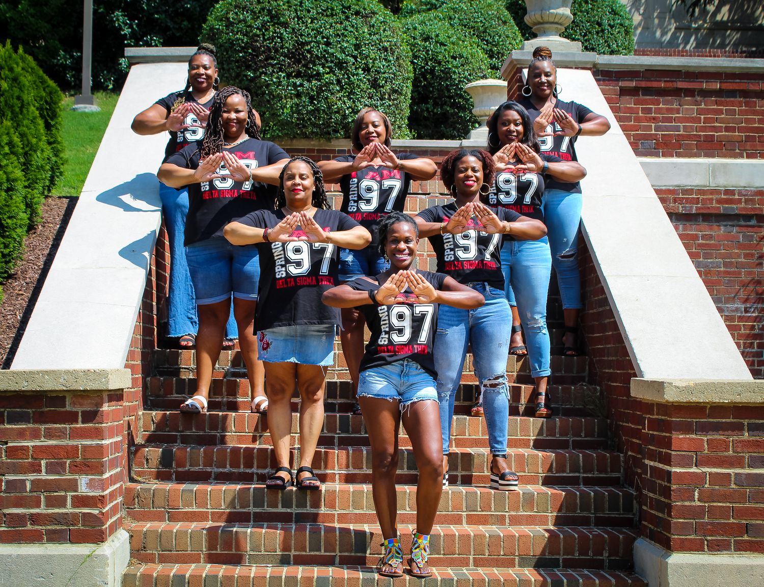A spirited group wearing matching sports jerseys poses on brick steps outdoors.