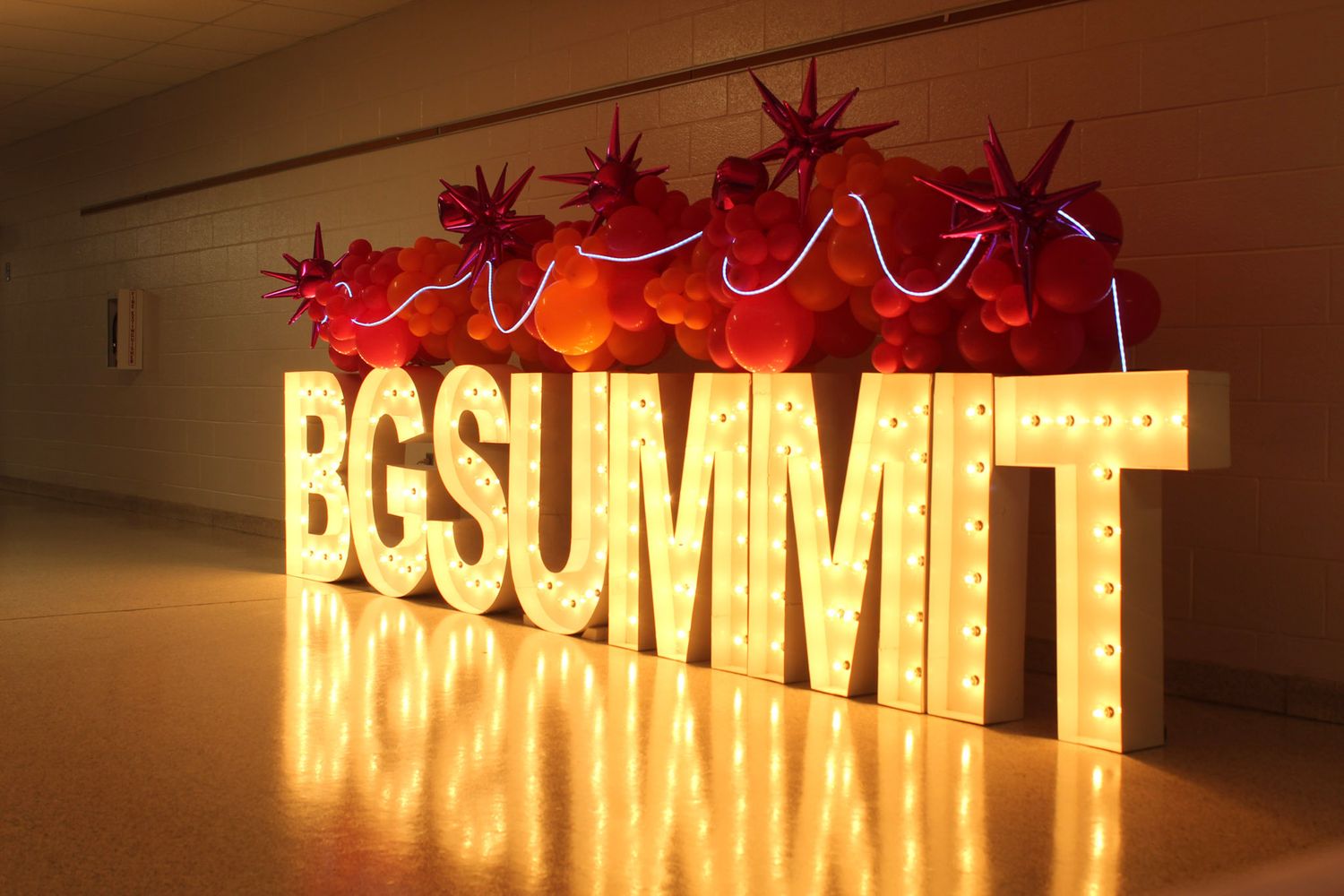 Illuminated marquee letters spelling BGSUMMIT with red star decorations on top at an event venue.