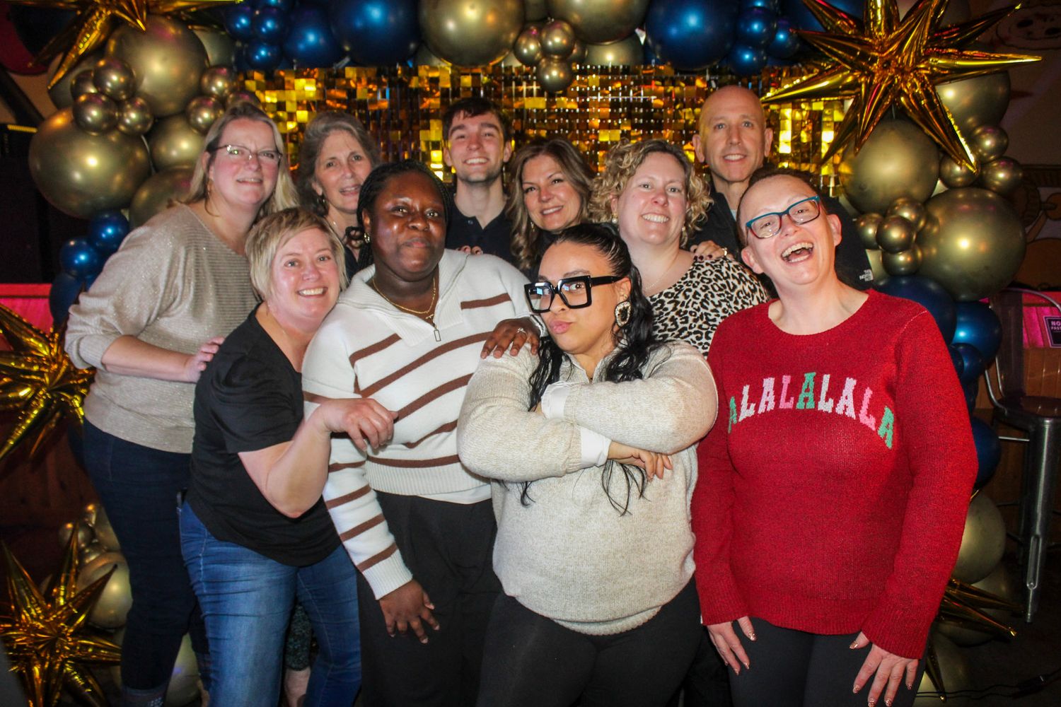 A group of people celebrating at a festive holiday party with twinkling lights and decorations in the background.