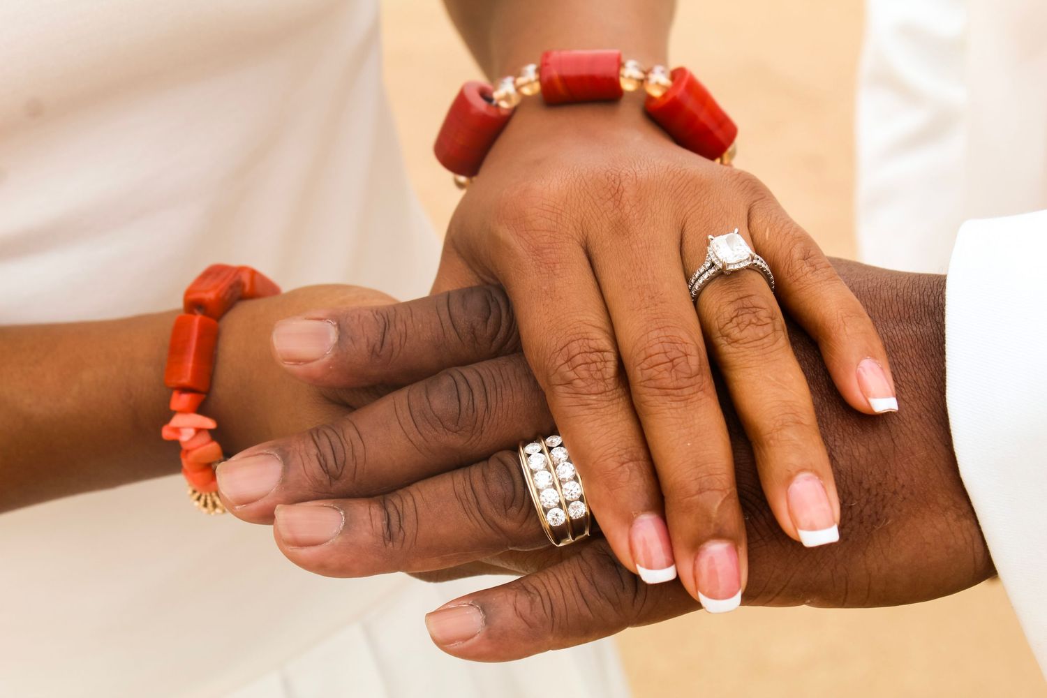 A series of close-up shots showing hands wearing red coral jewelry and white nail polish against a light background.