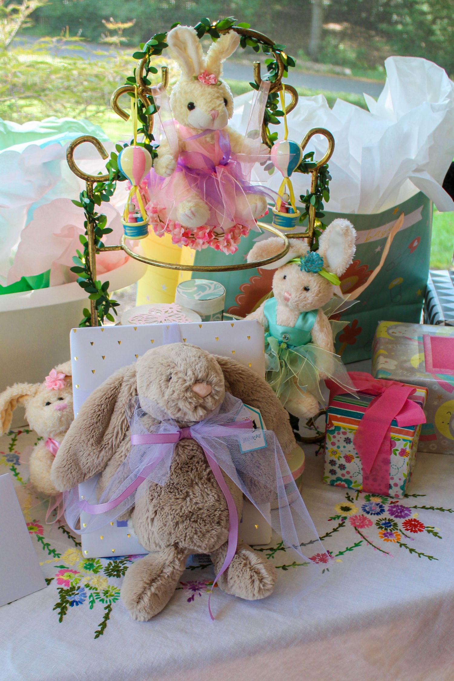 Decorative display of plush bunnies and Easter-themed items on a table with floral accents.