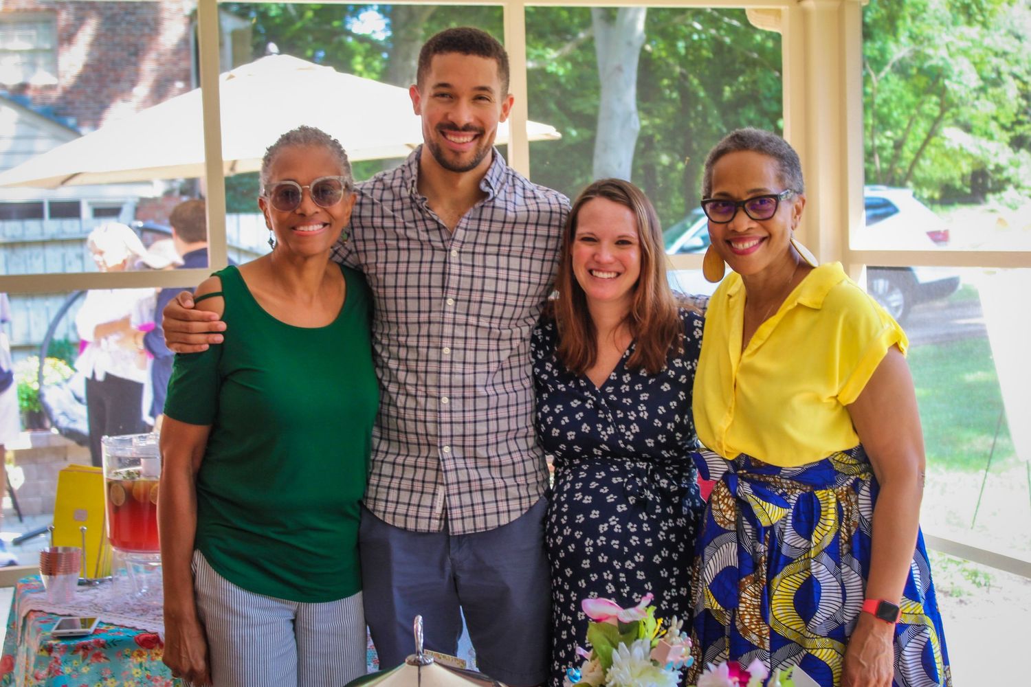 A group poses together at an outdoor summer gathering with drinks.