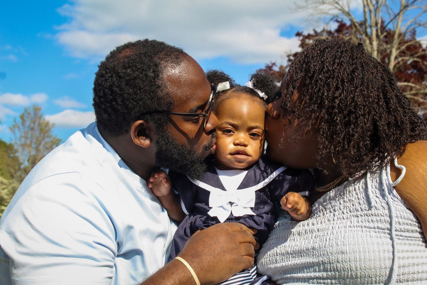Family members embrace in a group hug outdoors under blue sky.