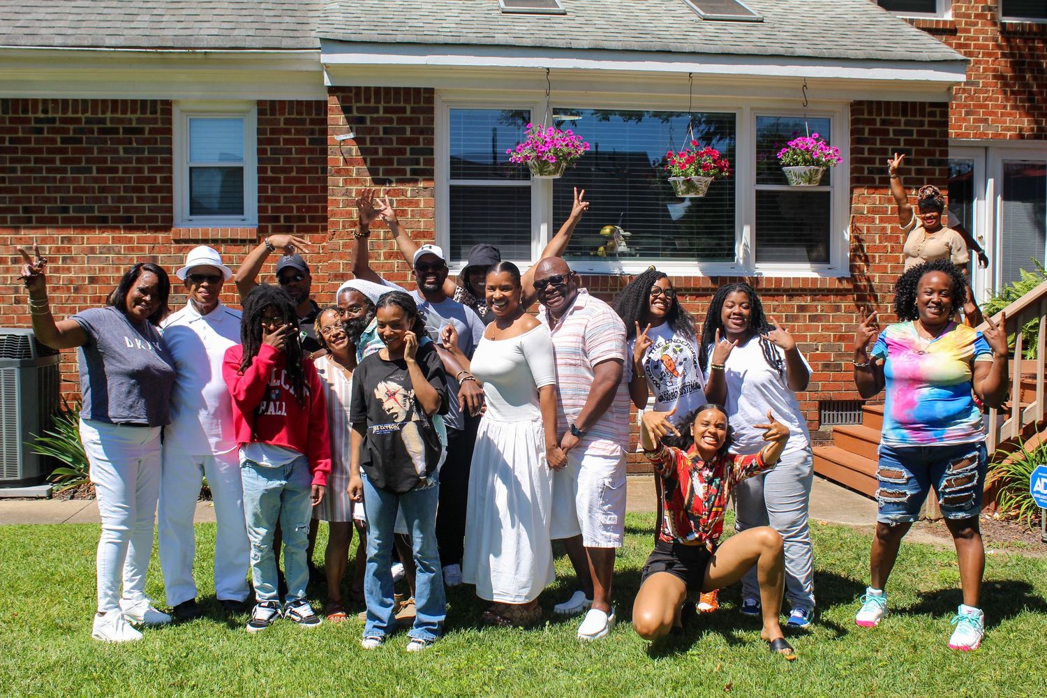 Large group poses together outside a brick building during a celebration.