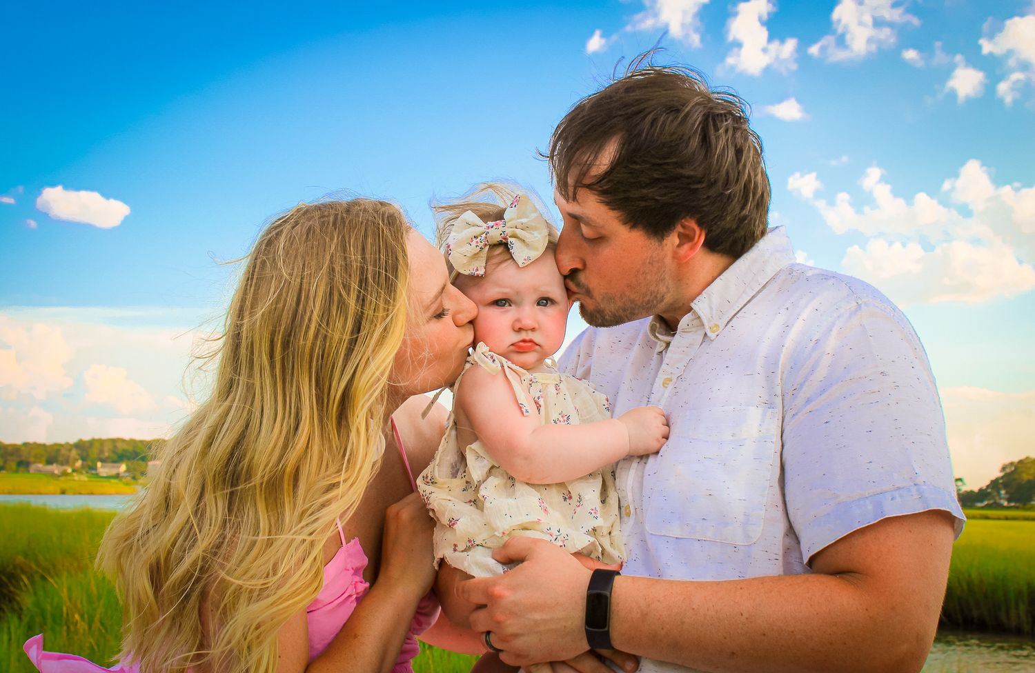 A tender family moment captured against a scenic waterfront backdrop at sunset.