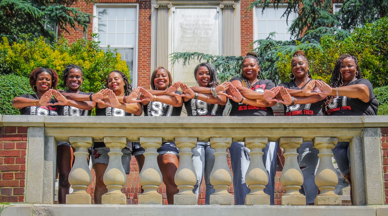 A cheerful group poses together on a stone balcony in matching attire.