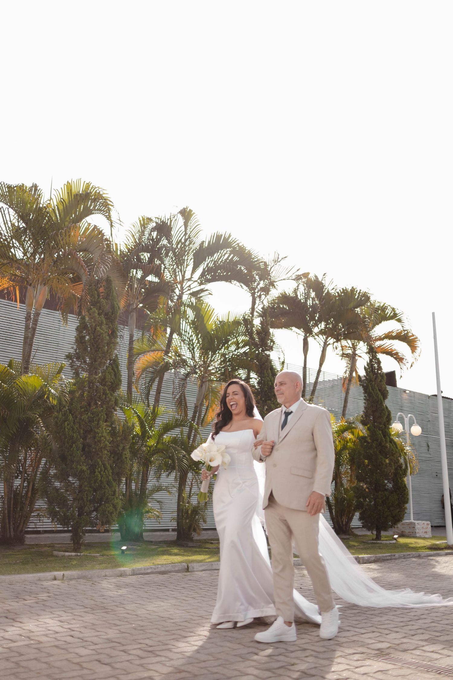 A couple dances and twirls in a tropical courtyard setting with palm trees and stone pavers during their wedding celebration.