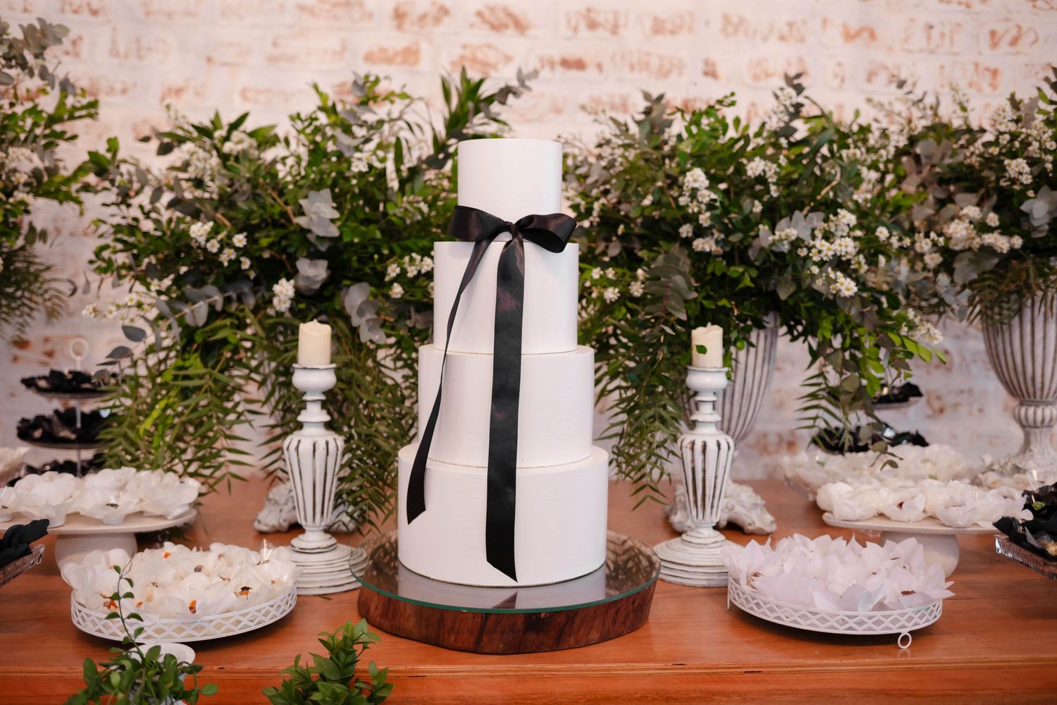 Wedding table decor features elegant white candles and greenery arrangements on rustic surface.