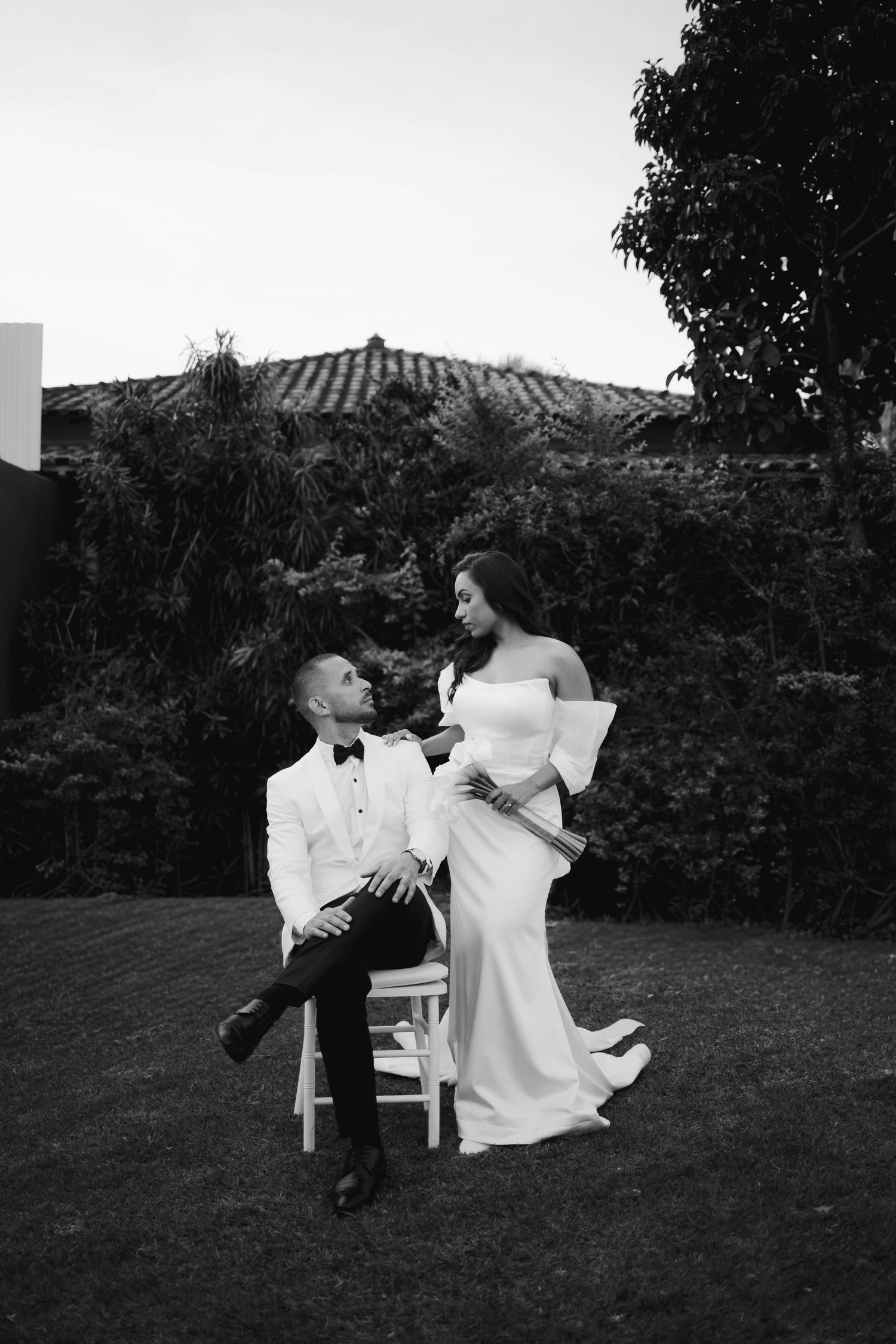 Couple relaxing on white outdoor furniture in a garden setting.