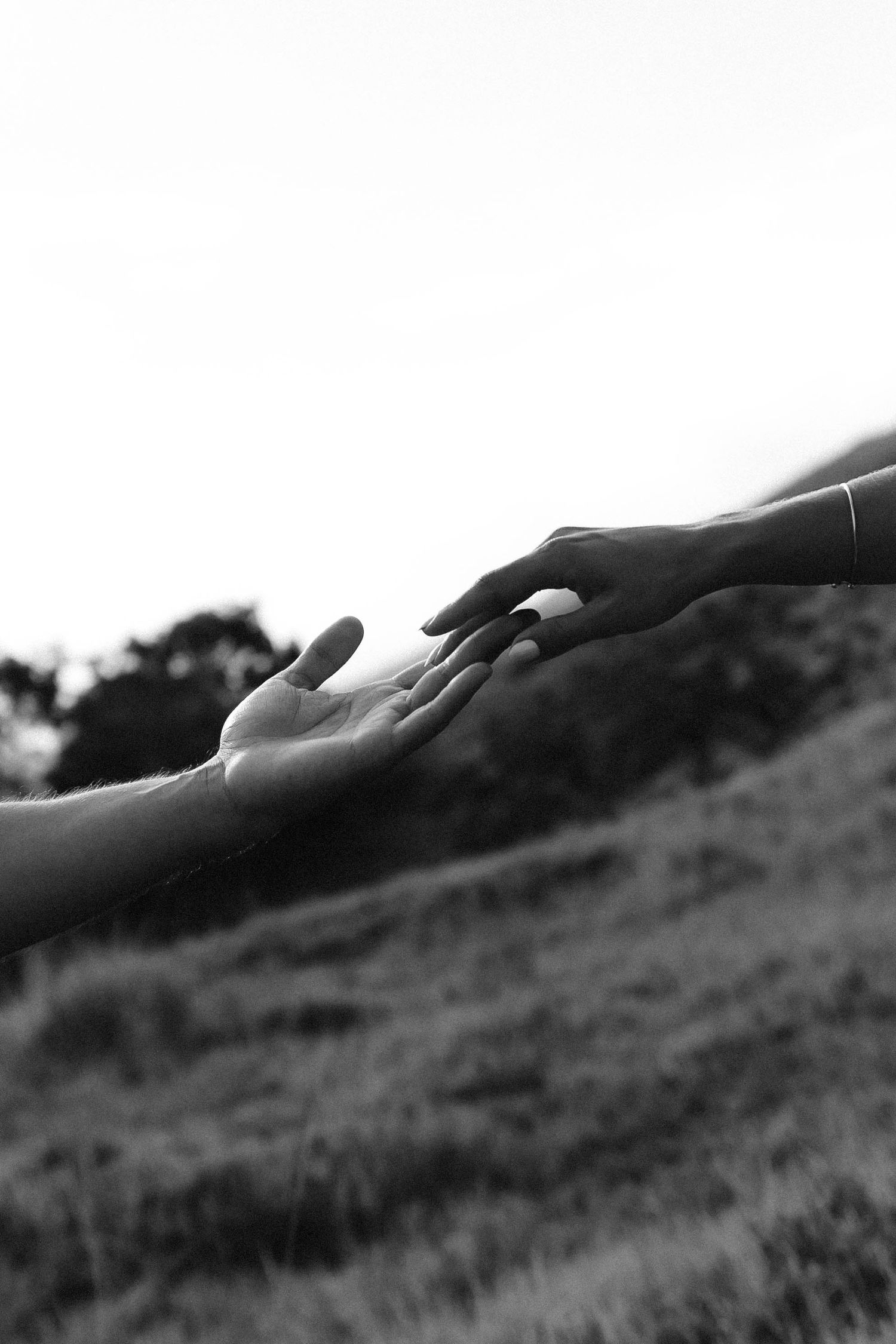 Artistic black and white landscape photograph showing silhouetted hands against a hillside.