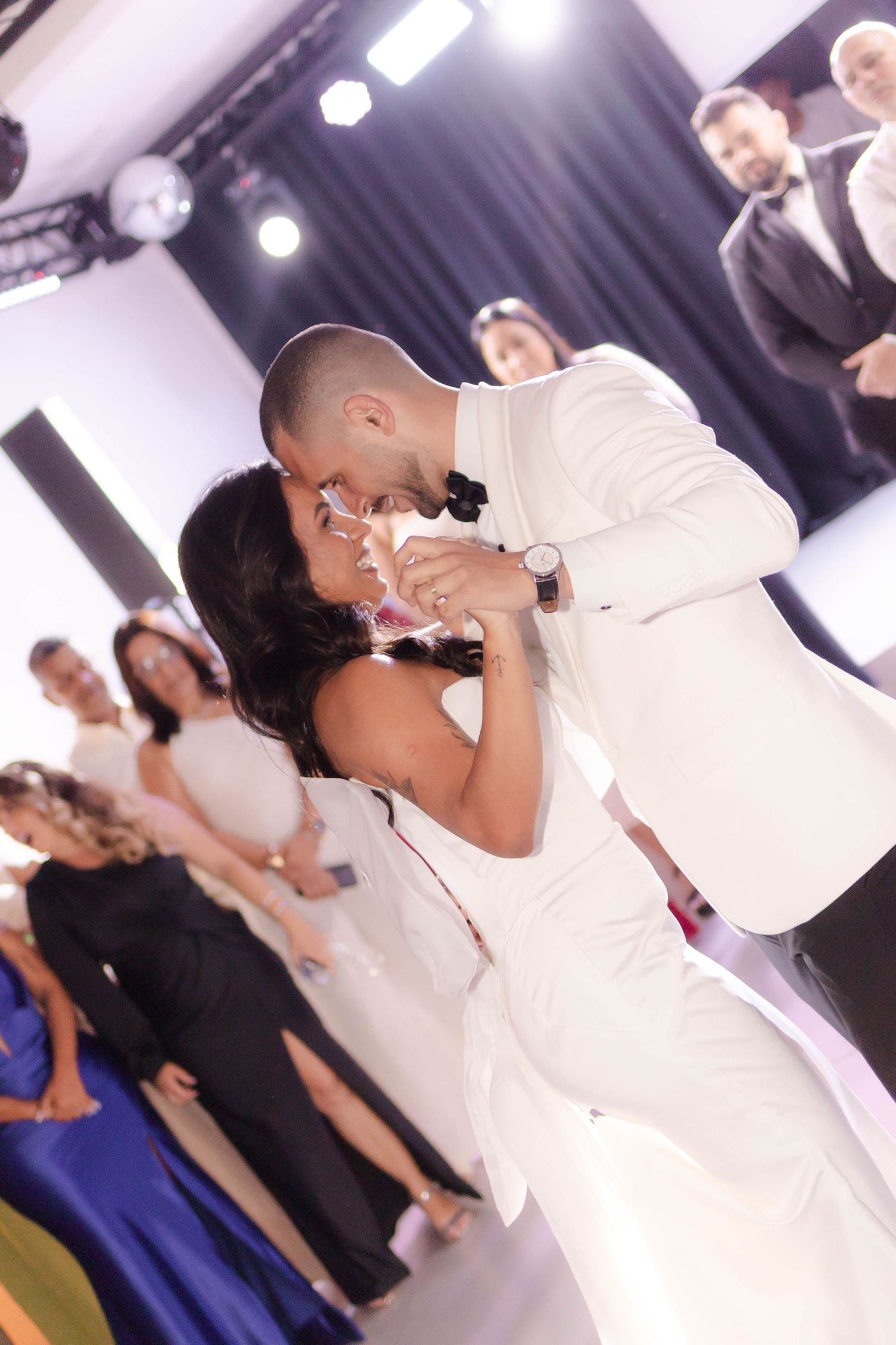Wedding couple sharing an intimate dance moment under stage lighting.