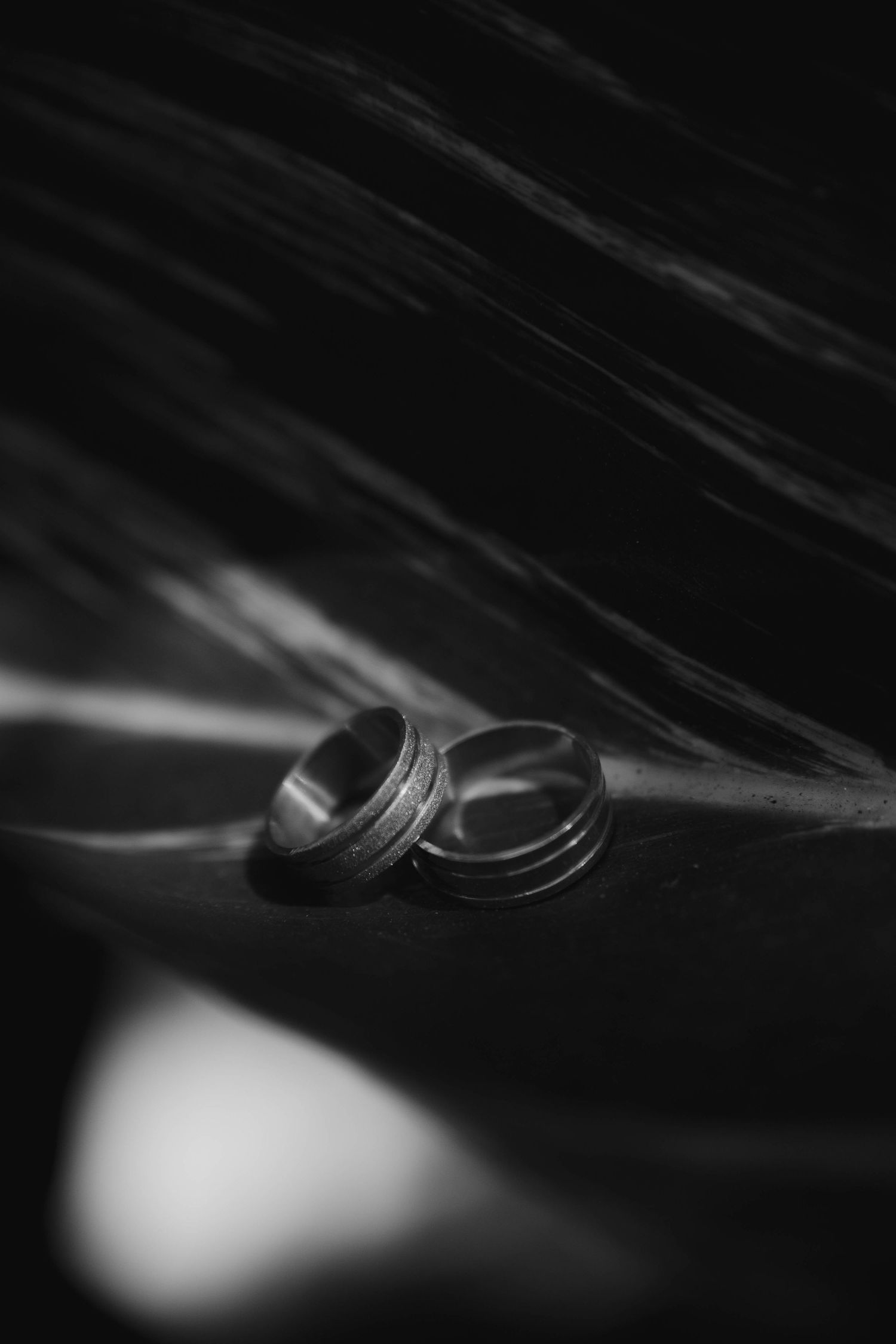 Macro photograph of wedding rings with dramatic lighting and shallow depth of field.