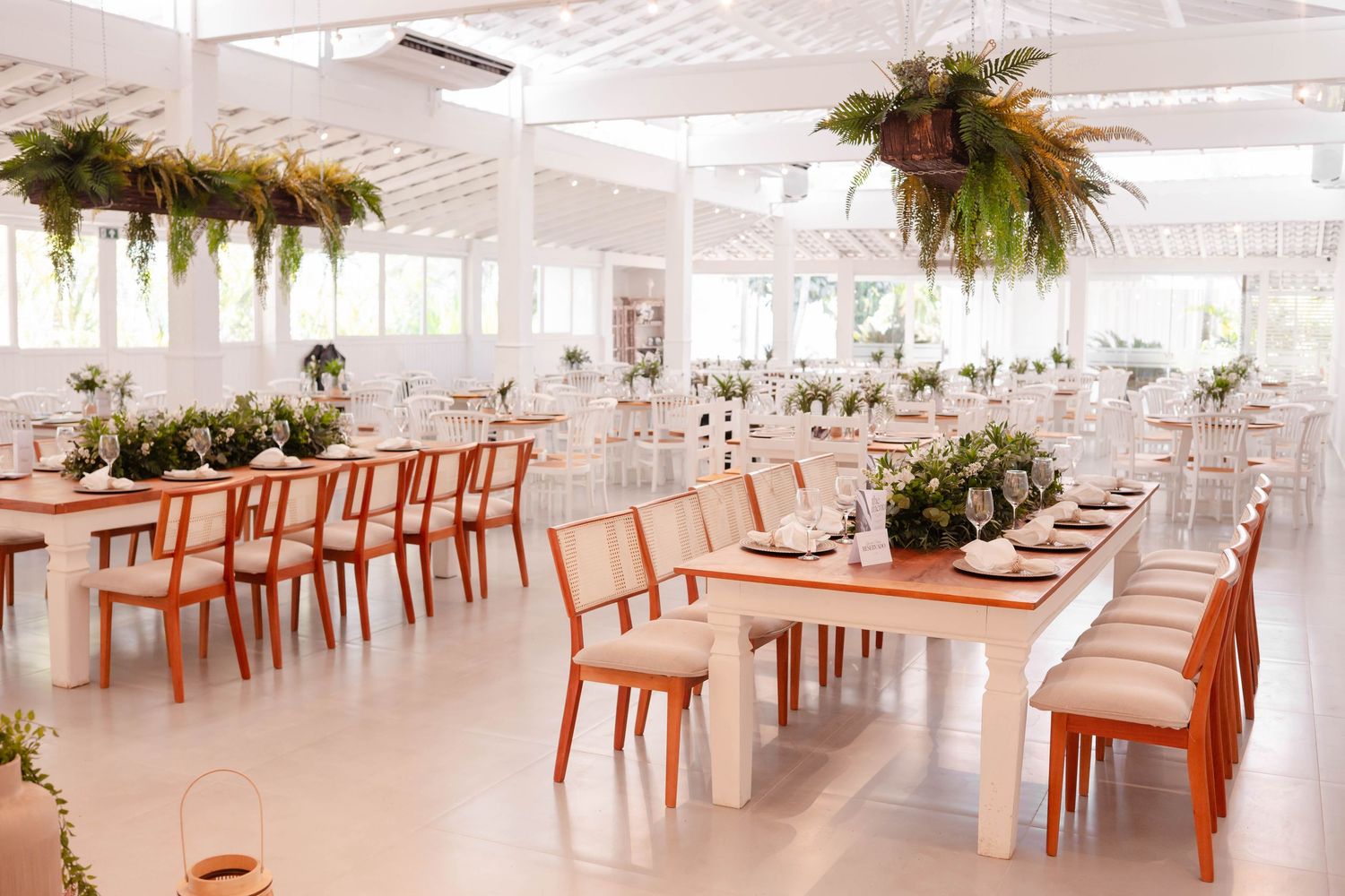 Modern white event space with coral chairs and hanging plants creating an elegant dining atmosphere.