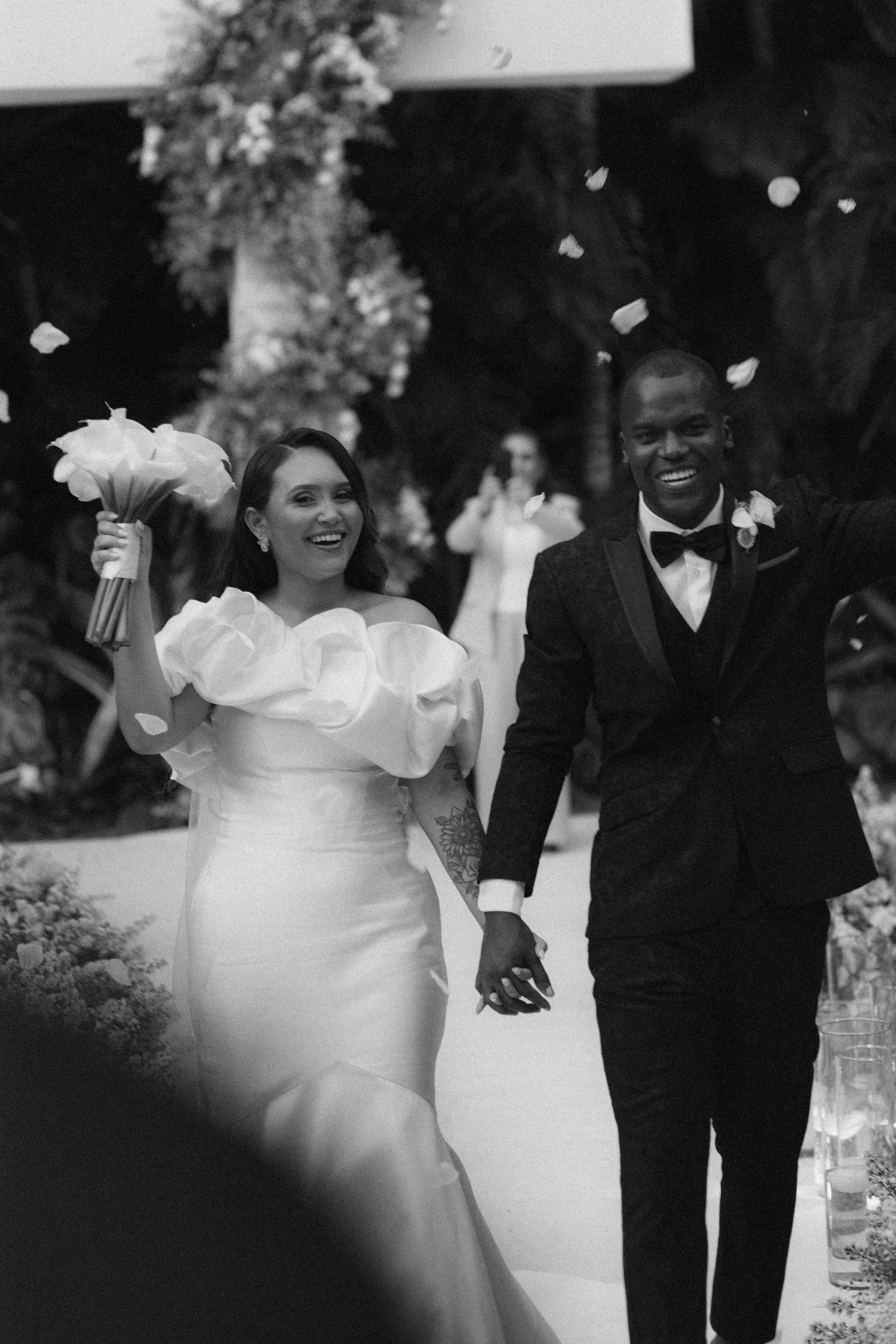 A joyful wedding couple walks together outdoors while sharing a candid moment.
