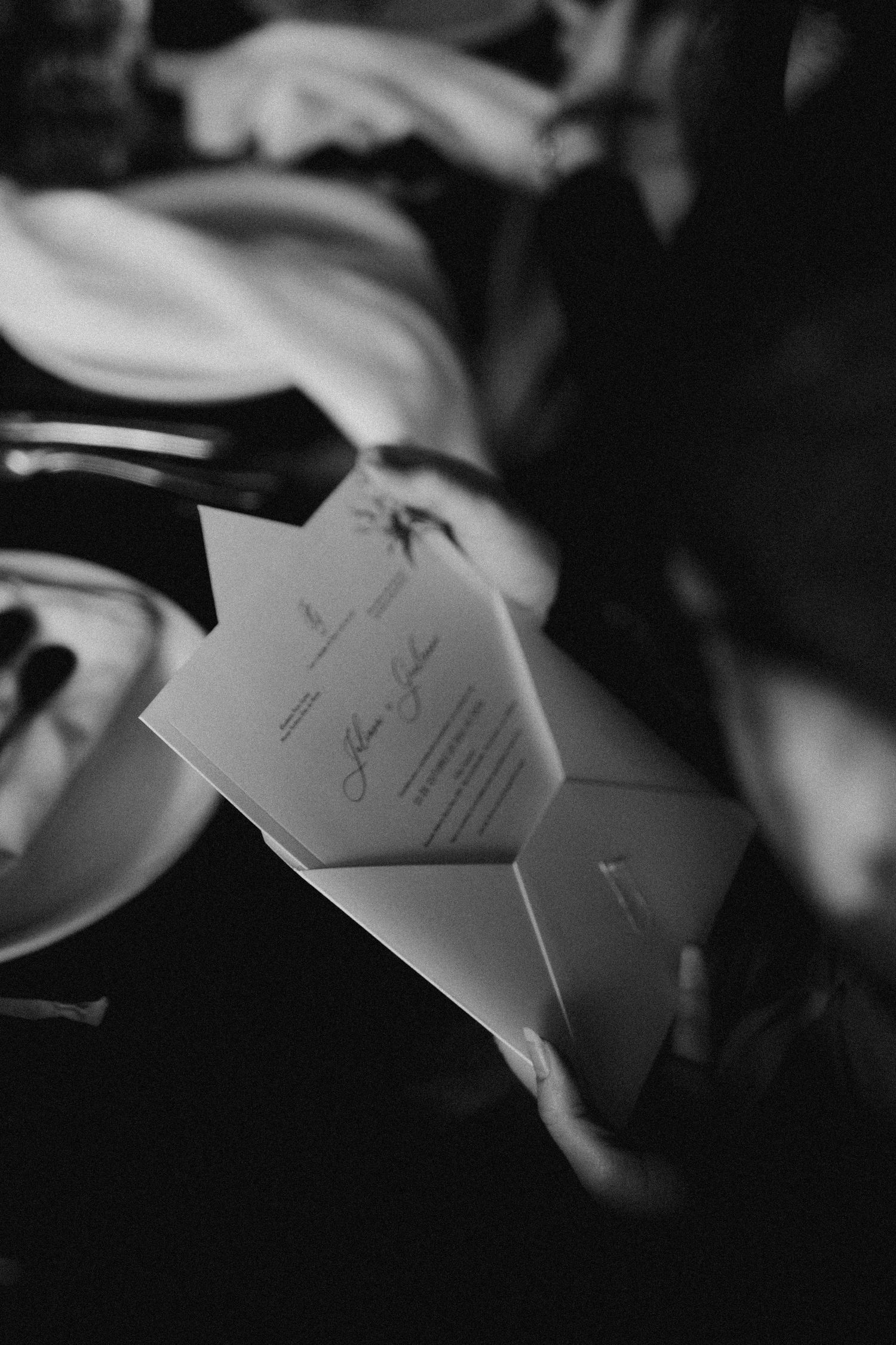 Black and white detail shot of wedding invitation cards and place settings.