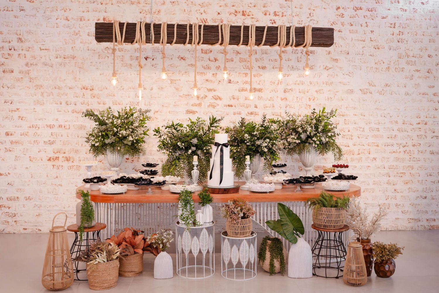 Elegant table setting with brick wall backdrop featuring floral arrangements and glassware.