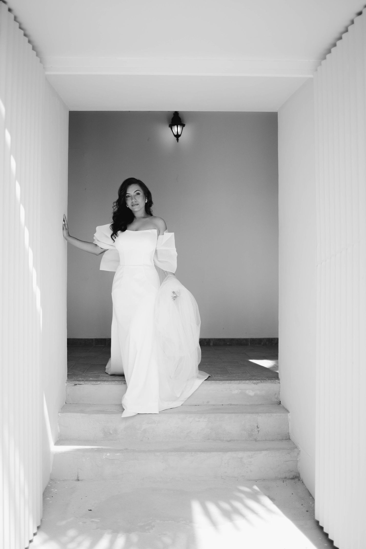 A black and white photo series shows a figure in white dress moving through minimalist architectural spaces.