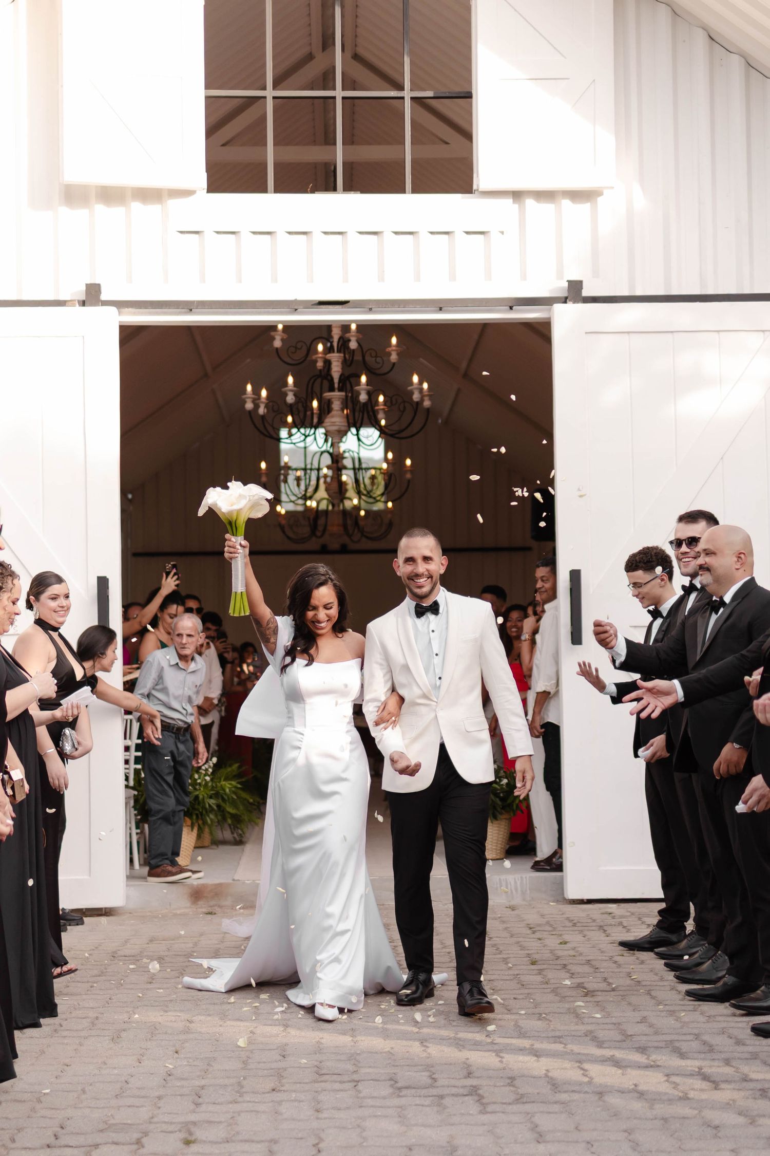 Wedding guests celebrate by tossing rice at the newlyweds as they exit the white church building.