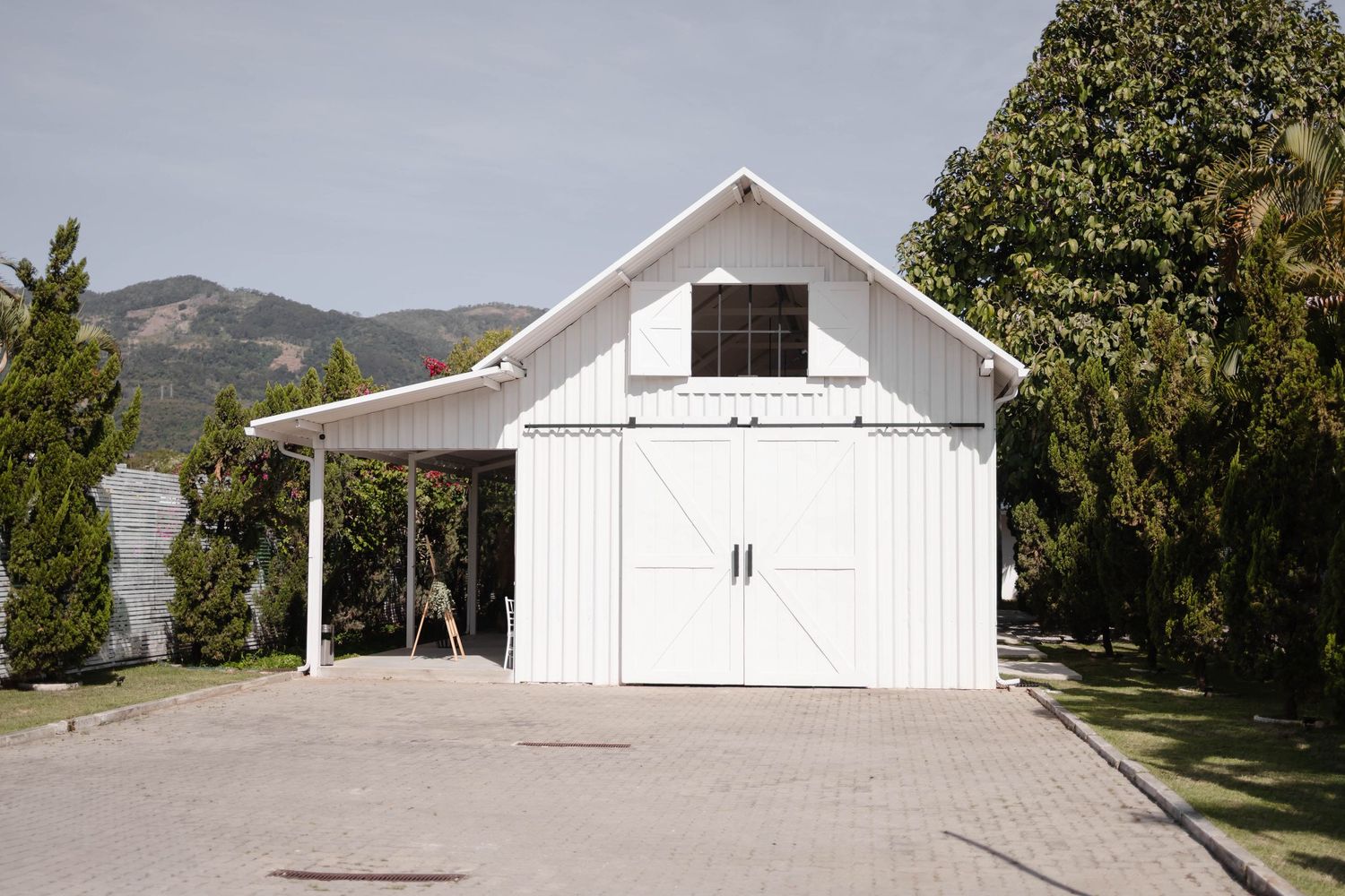 Long view of white barn wedding venue with mountains in background.
