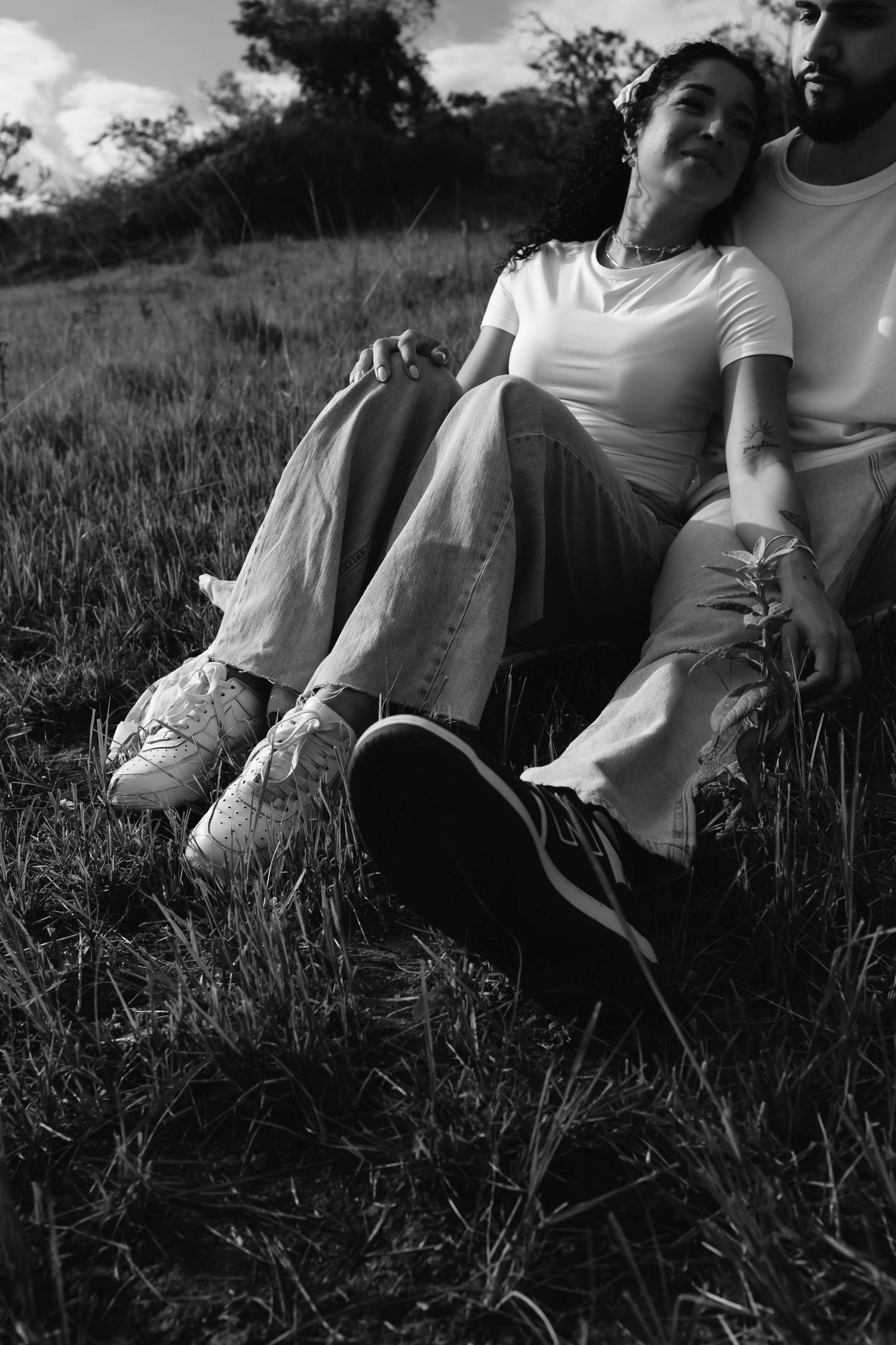 A black and white photo series shows people relaxing in tall grass on a sunny afternoon.