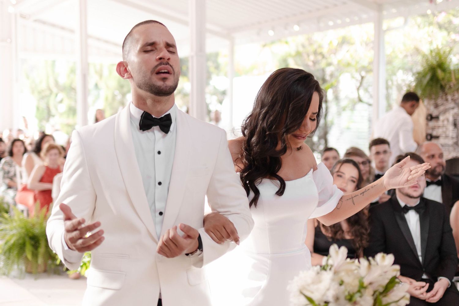 Wedding guests dance and celebrate together at an elegant reception under a white tent.