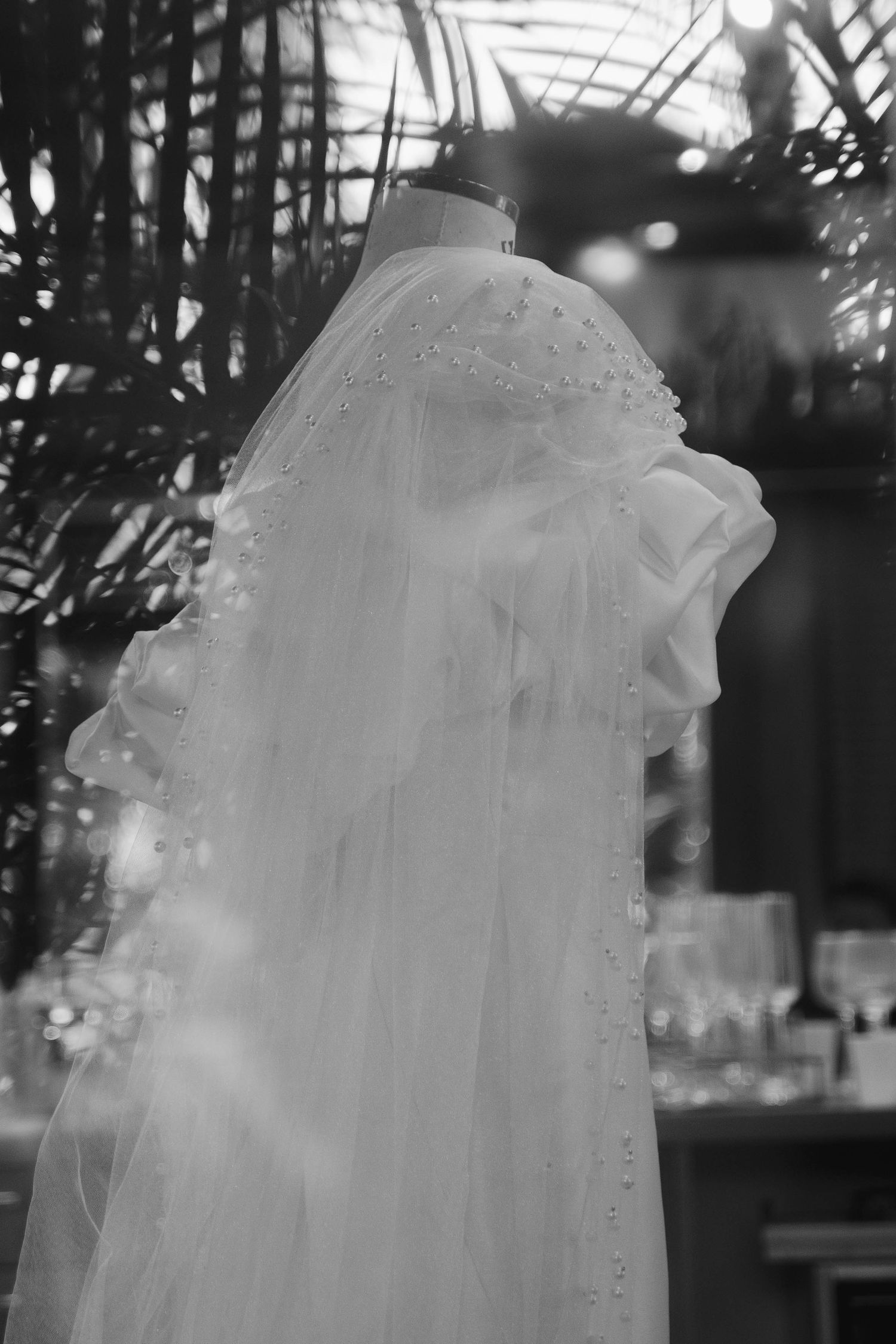 Ethereal white wedding dress details captured in soft focus black and white photography.