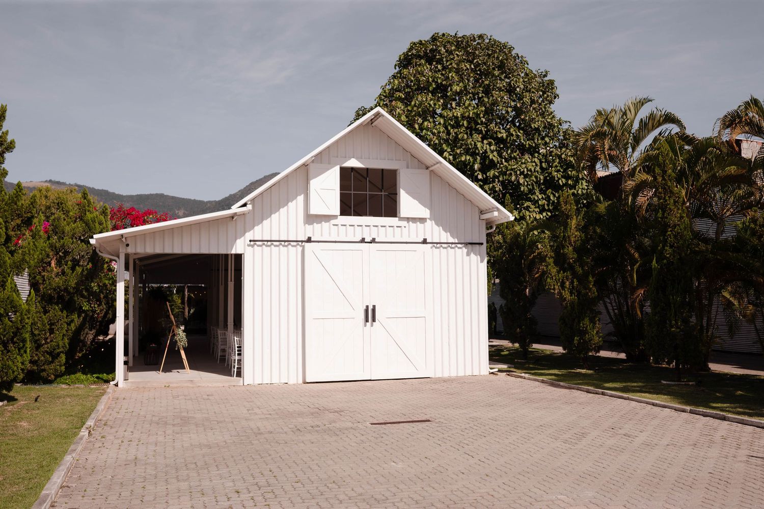 A white garage door with decorative hardware and windows against a white exterior wall in a residential setting.