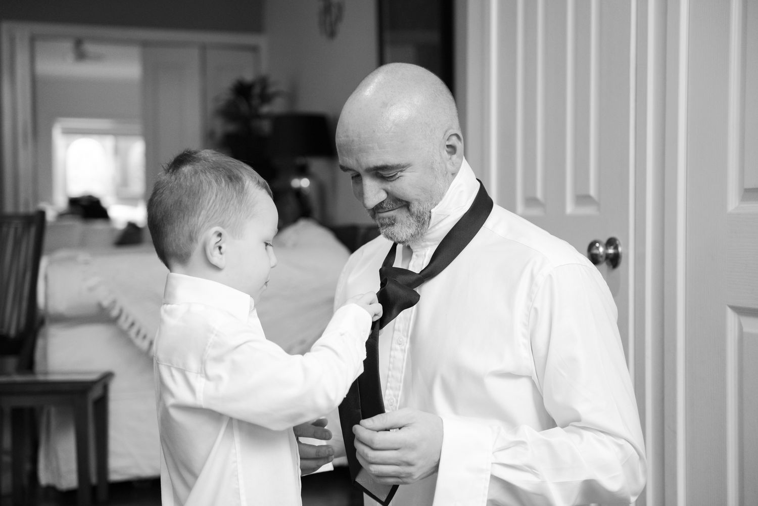 Black and white photo series showing tender moments between a parent and son while groom gets ready.