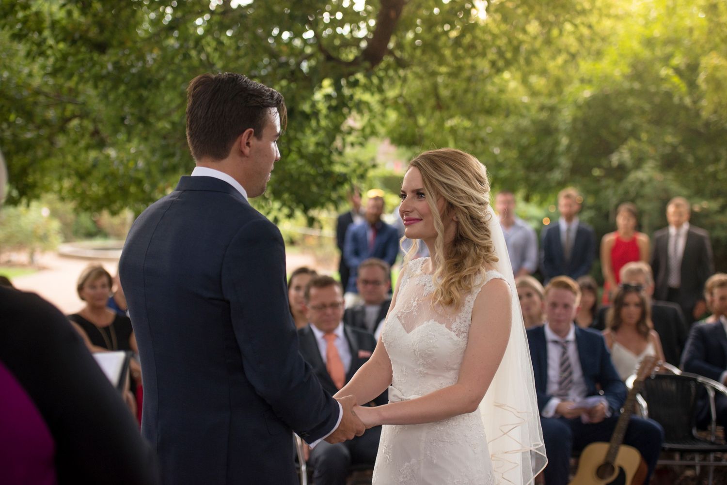 Outdoor wedding ceremony scene with guests gathered under golden evening light.