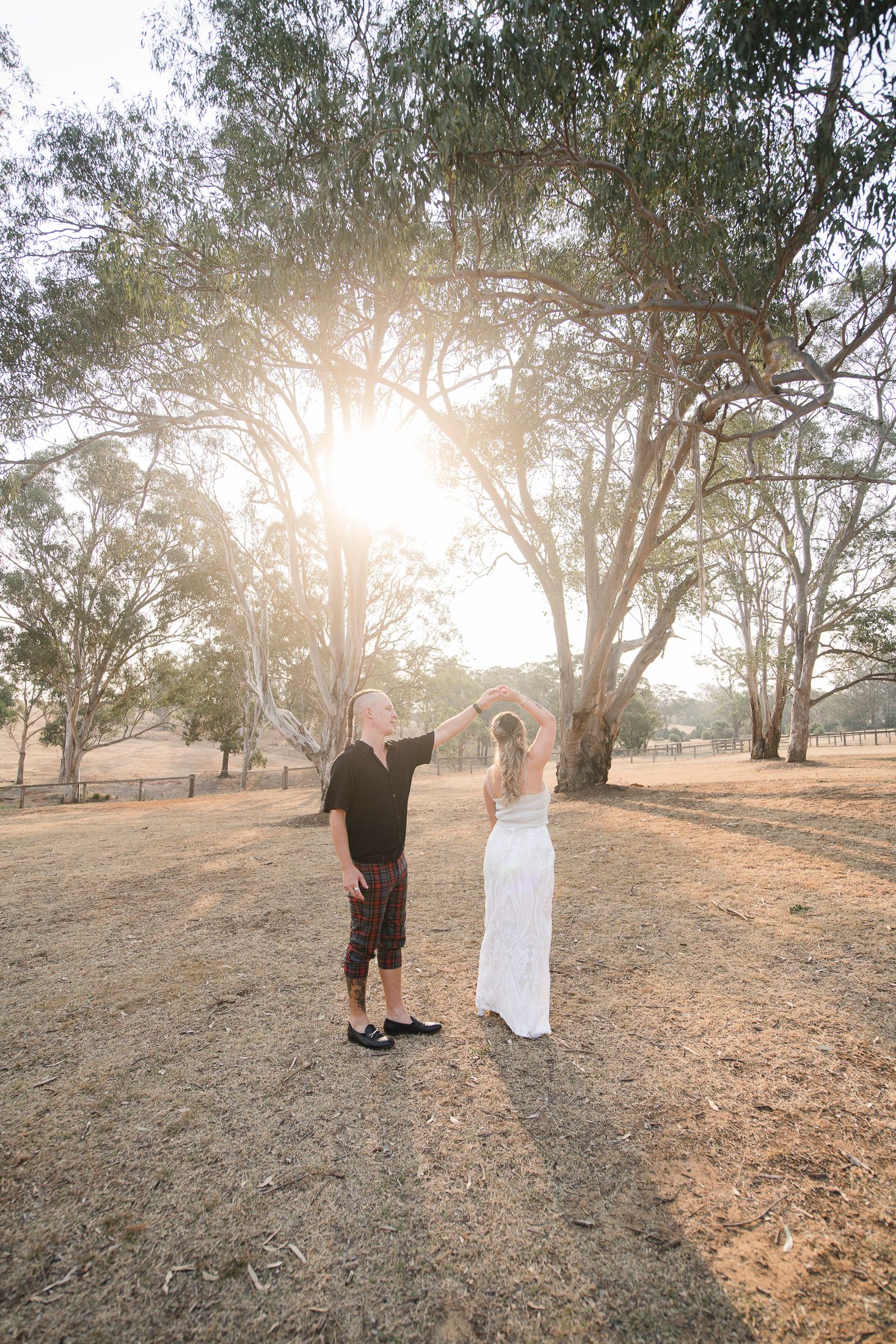Bride and groom having with during reception with tall eucalyptus trees in the background.