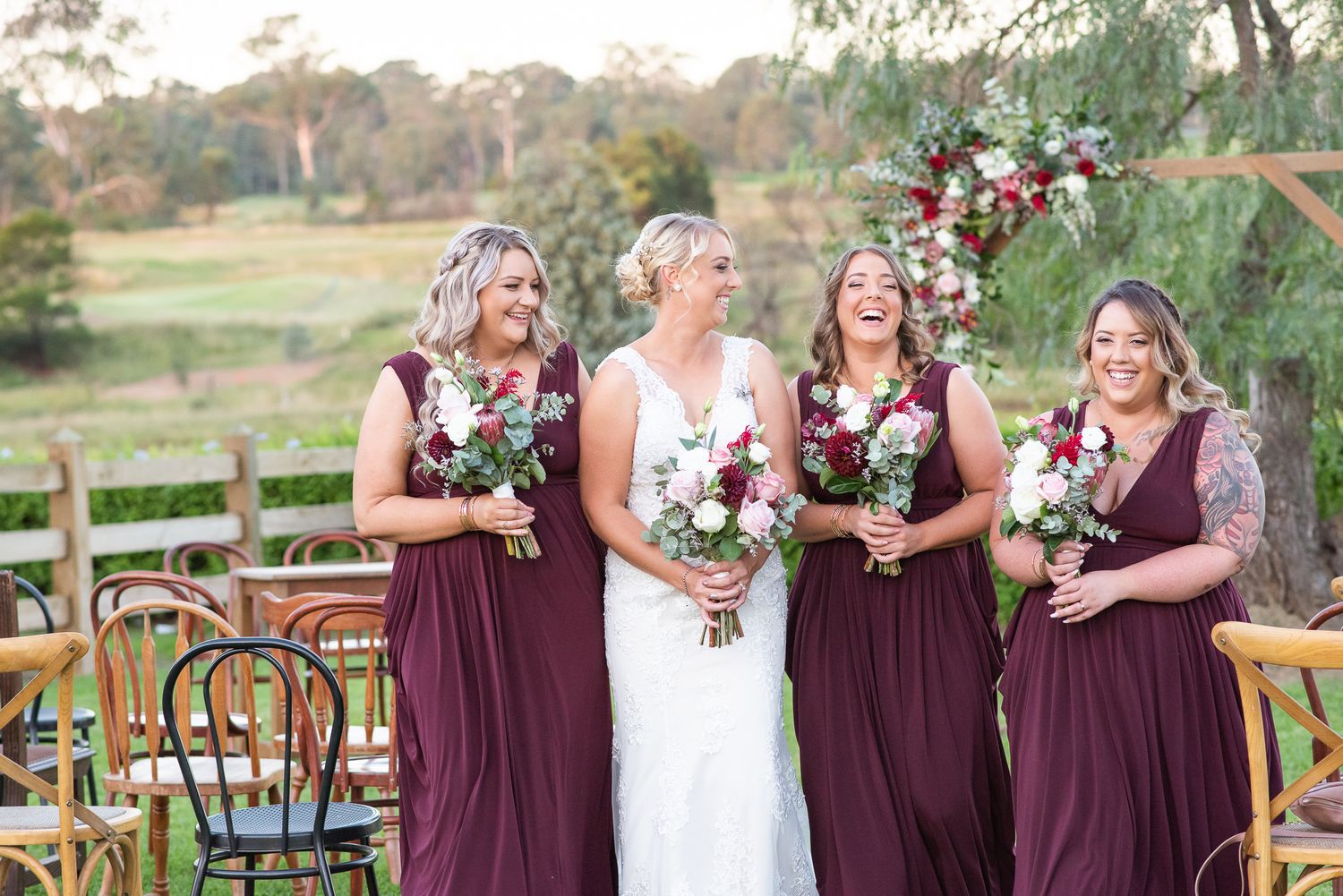Bride with bridesmaids smiling with flowers.