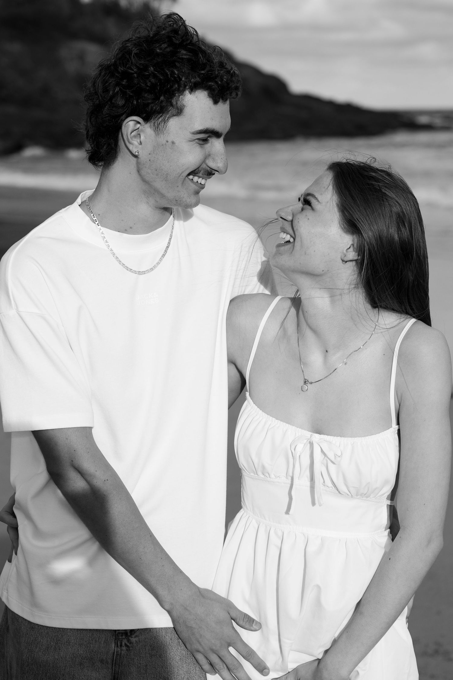Couple laughing during their photo session on a beach during sunset in Kiama.