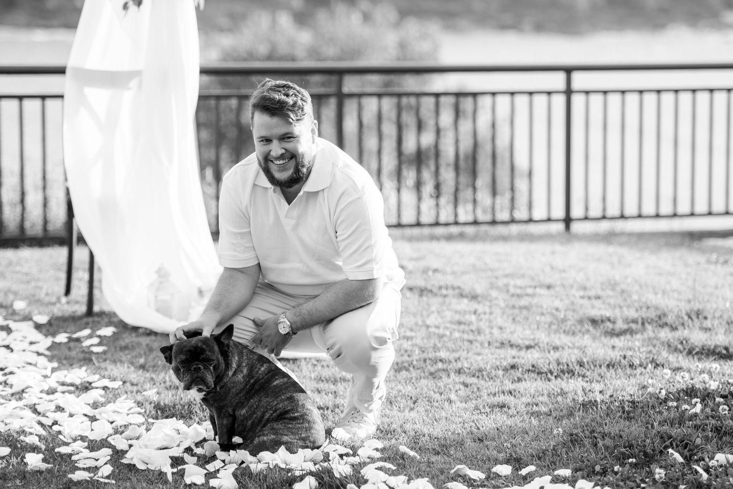 A series of black and white photos showing someone playing and interacting with a small dog in a backyard setting.