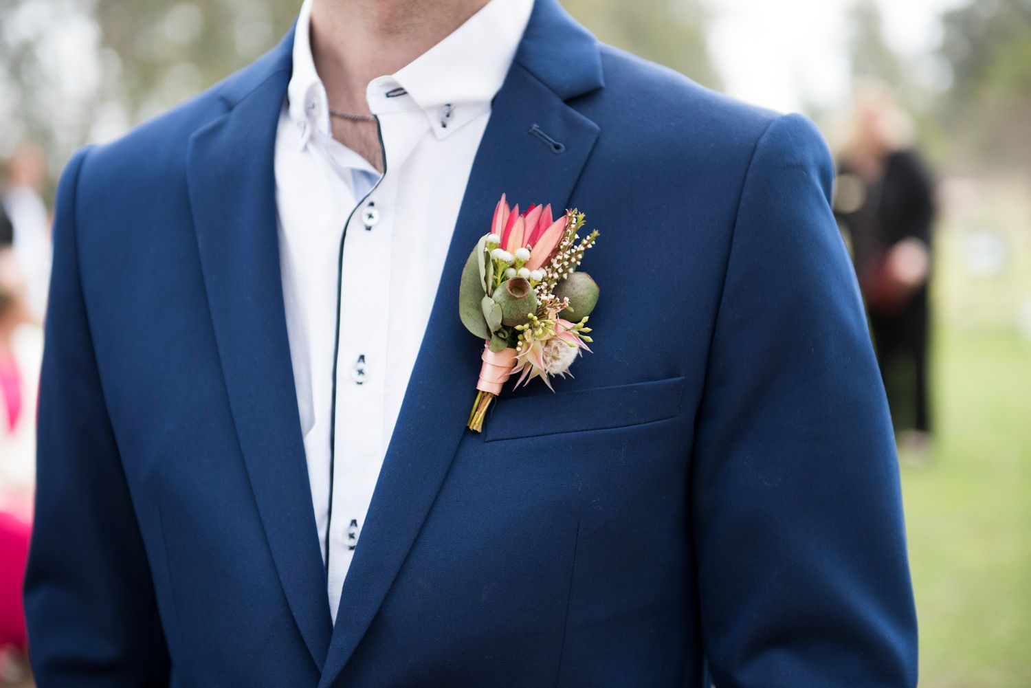 A close-up view of an Australian native boutonniere pinned to a navy blue suit jacket.