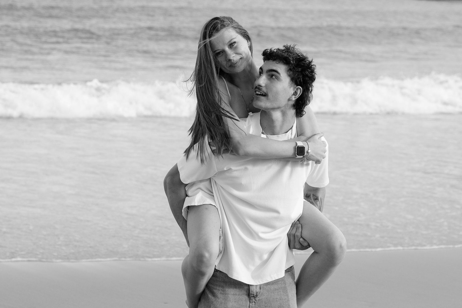 A series of black and white beach photographs showing joyful moments and playful interactions at the seashore.