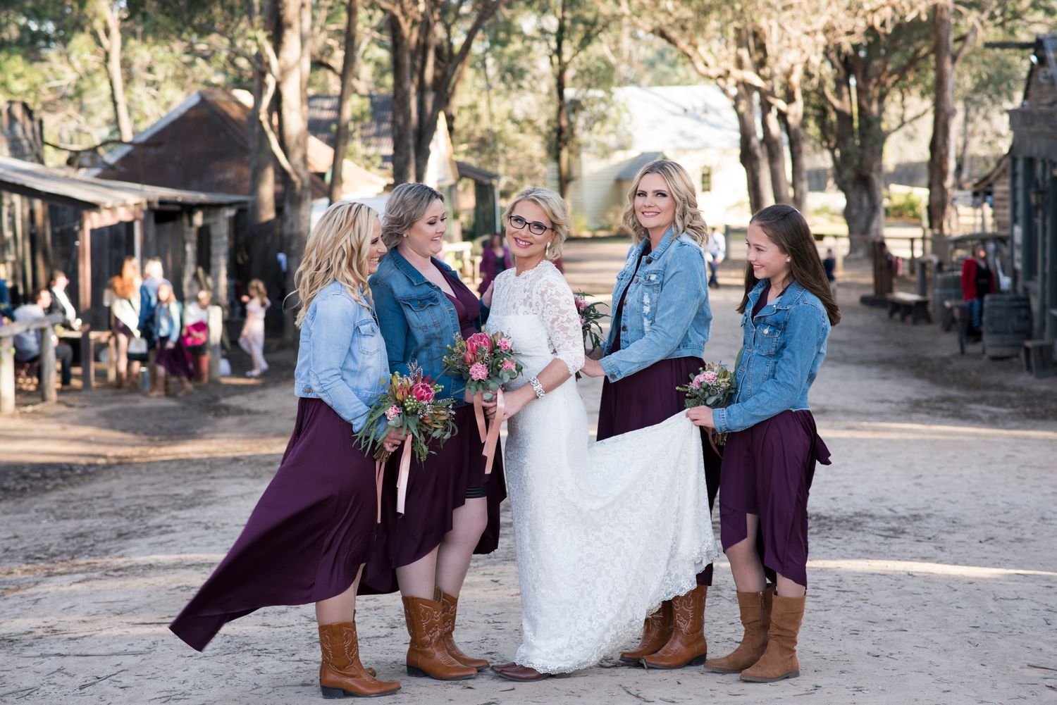 Bride with bridesmaids outdoors at a rustic venue.