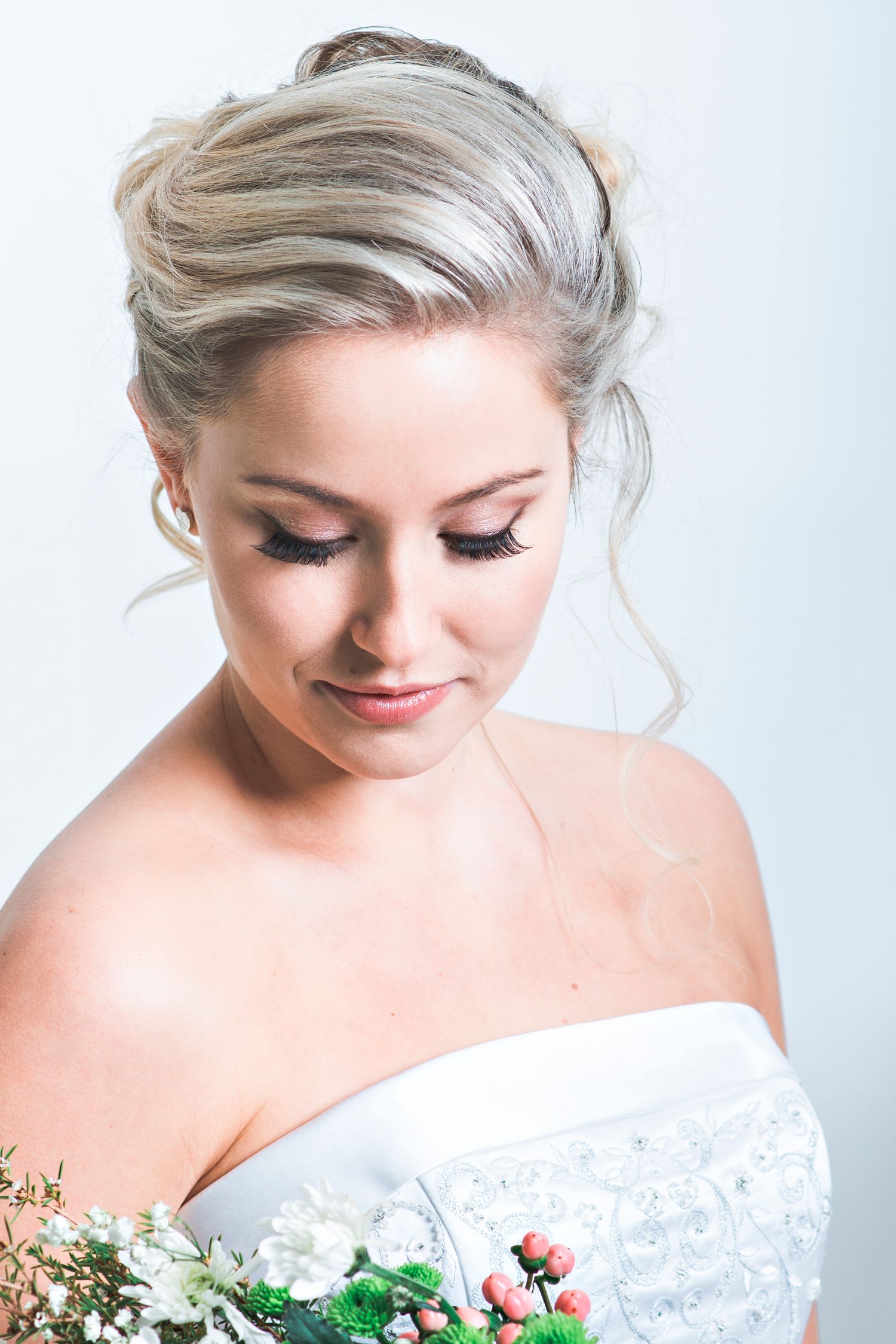 Bridal portrait in white lace off-shoulder dress against light background.