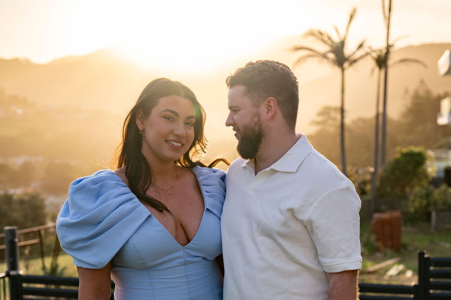 Romantic couple embraces during golden hour sunset in Kiama with warm glowing light.