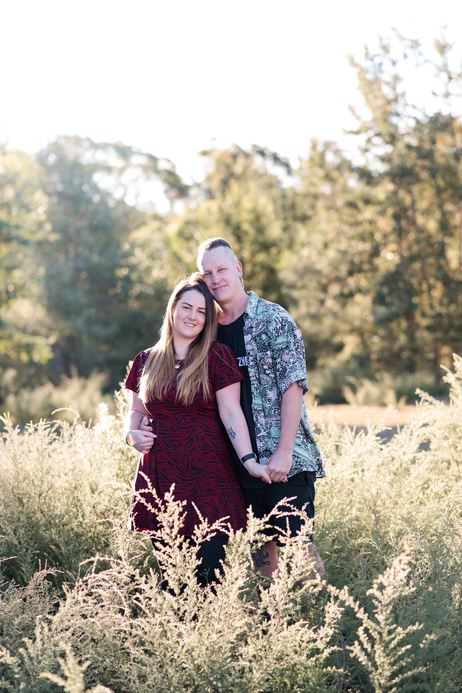 A couple shares a joyful moment together in a sun-drenched field.
