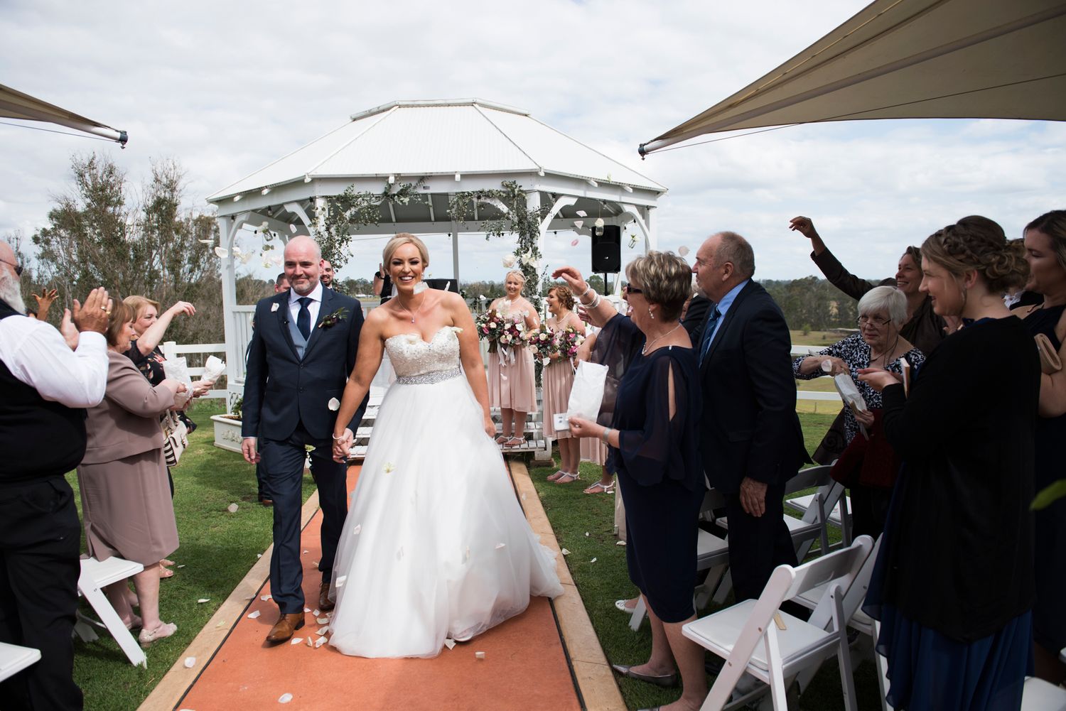 A sequence of outdoor wedding ceremony moments captured at a scenic venue with guests and umbrellas.