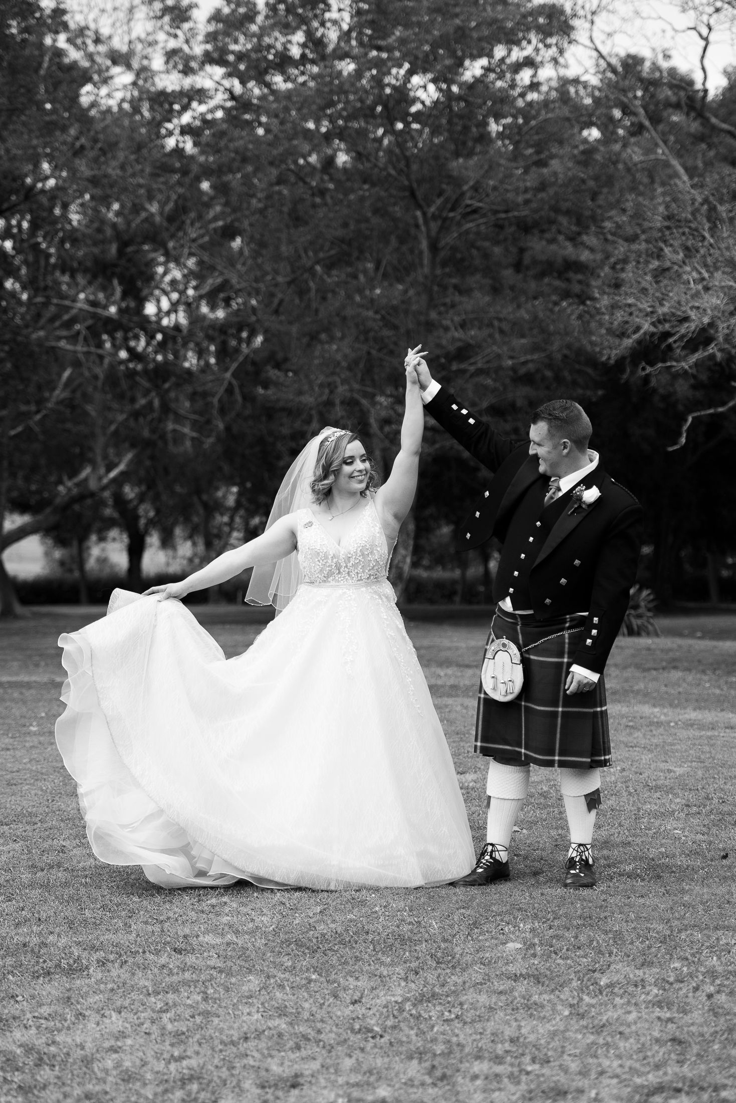 A couple in wedding attire lies playfully on grass in a sequence of black and white photos showing movement and joy.