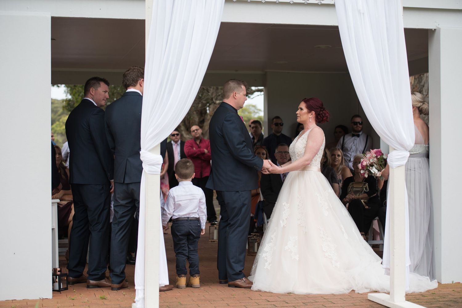 Wedding reception setup with white fabric draping and guests mingling in background.