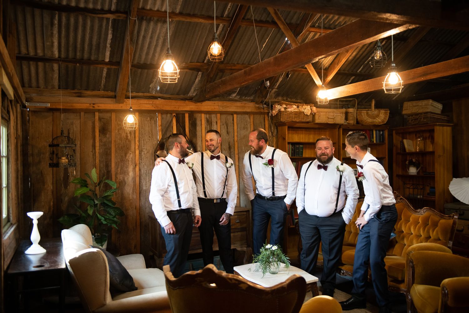 Groom with groomsmen getting ready in rustic barn.