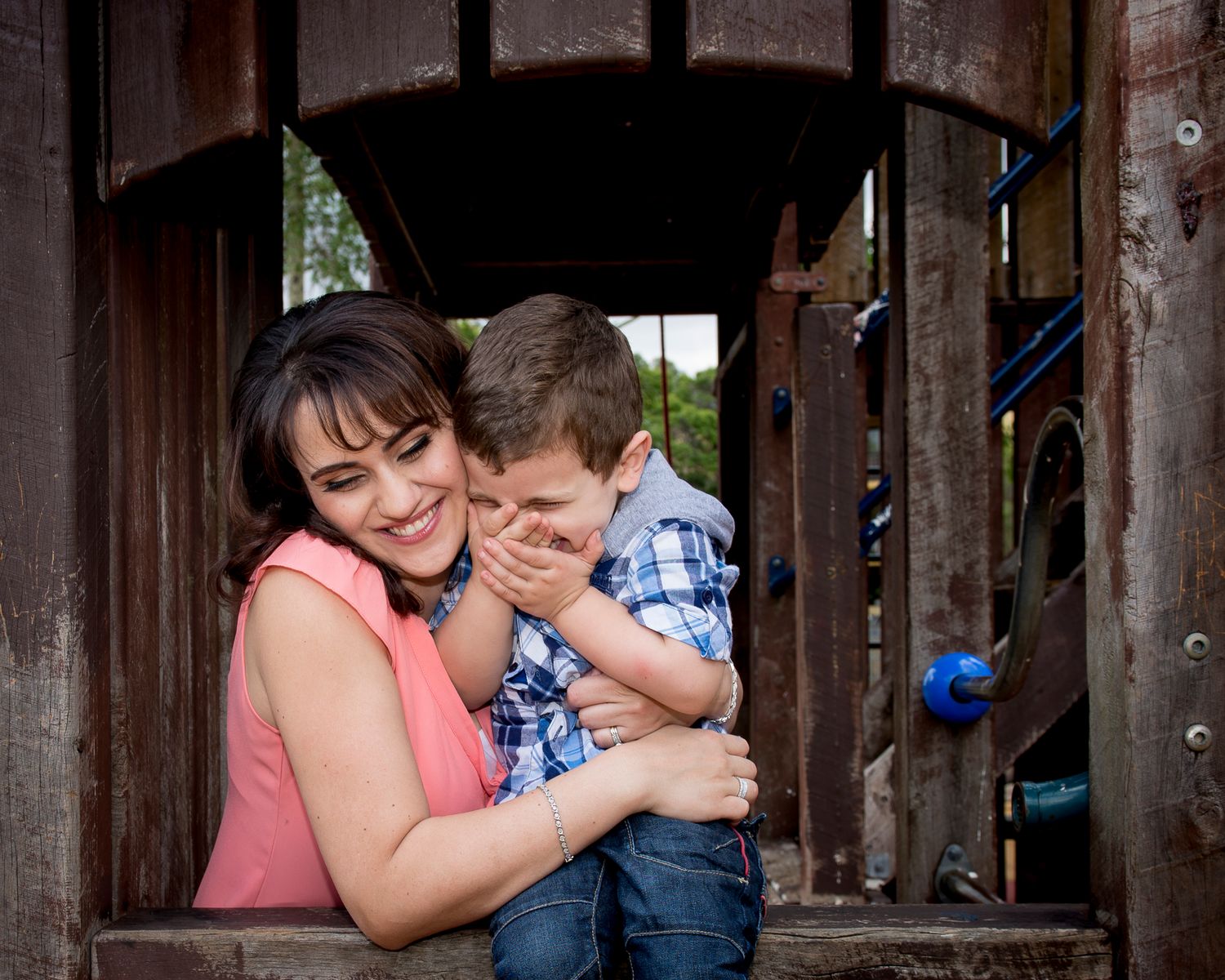 Family shares tender moments together on rustic wooden play area.