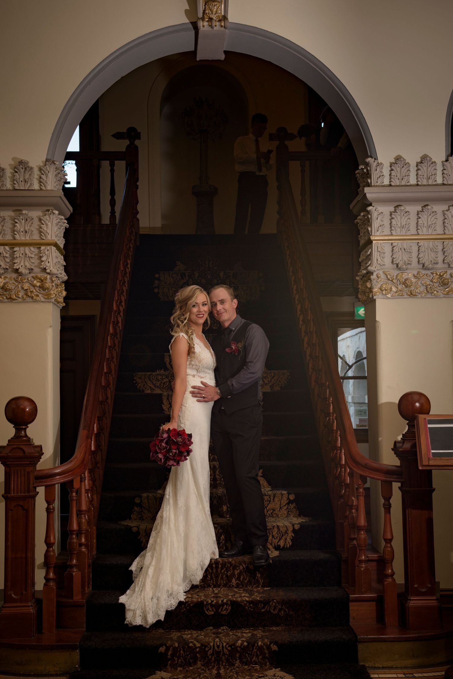 A couple shares a romantic dance moment in a dimly lit venue with ornate wooden pillars and decorative trim.
