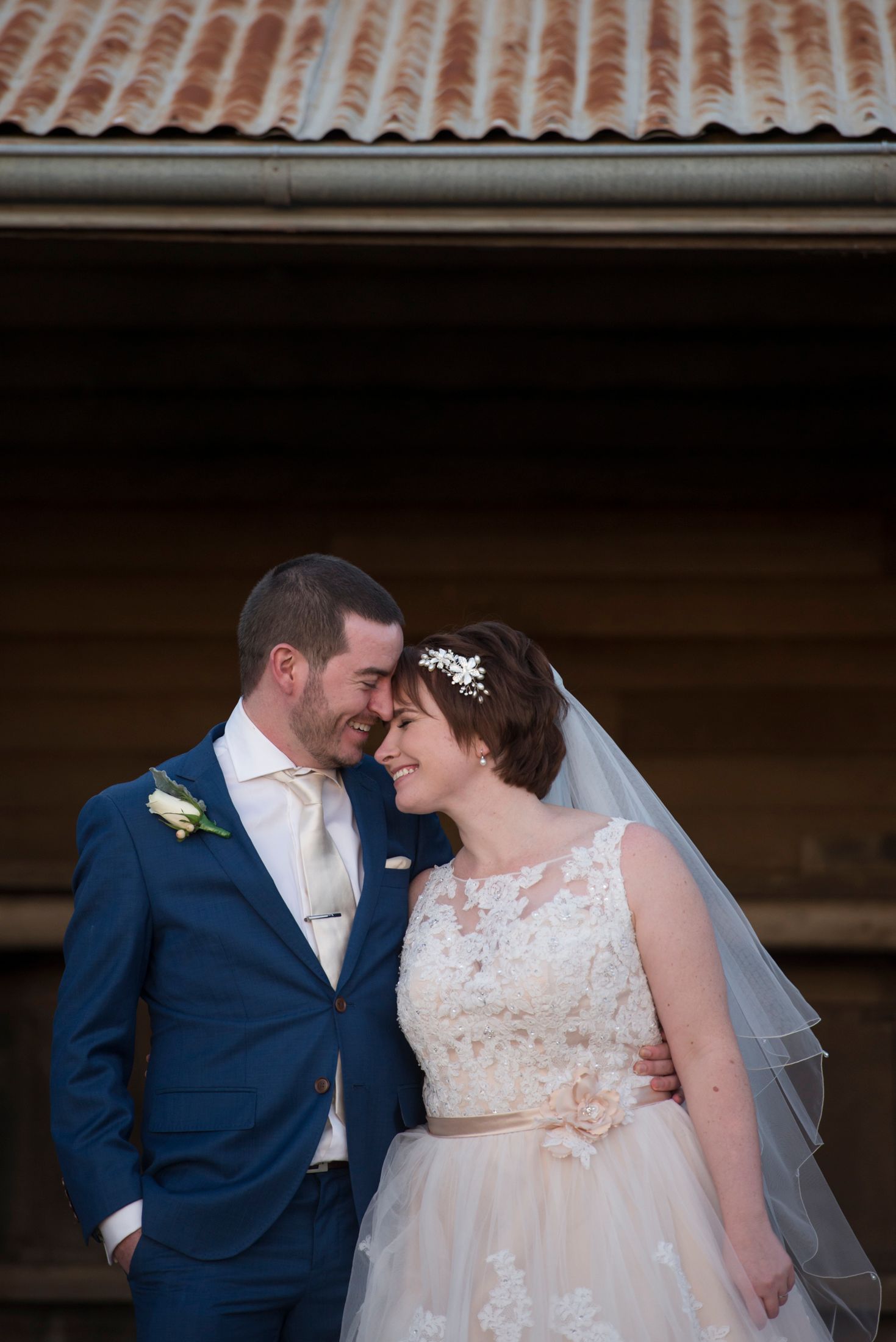 Wedding couple shares intimate moment under rustic terracotta roof.