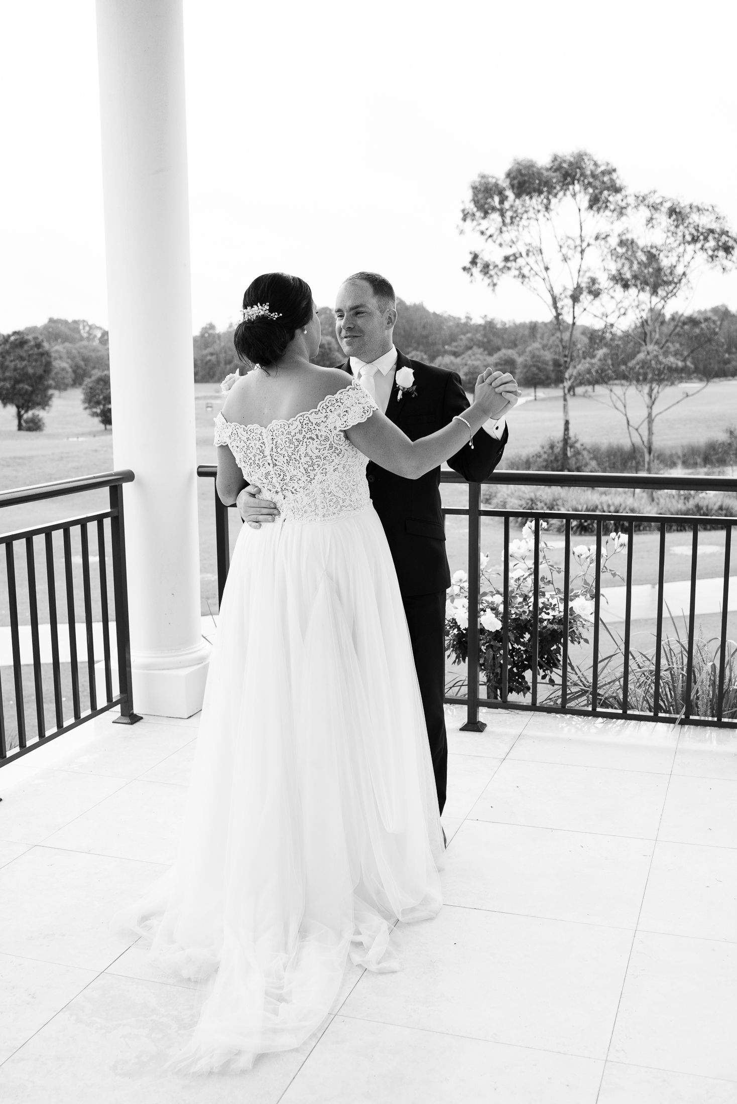 A romantic dance sequence on a balcony with a flowing white wedding dress captured in black and white photography.