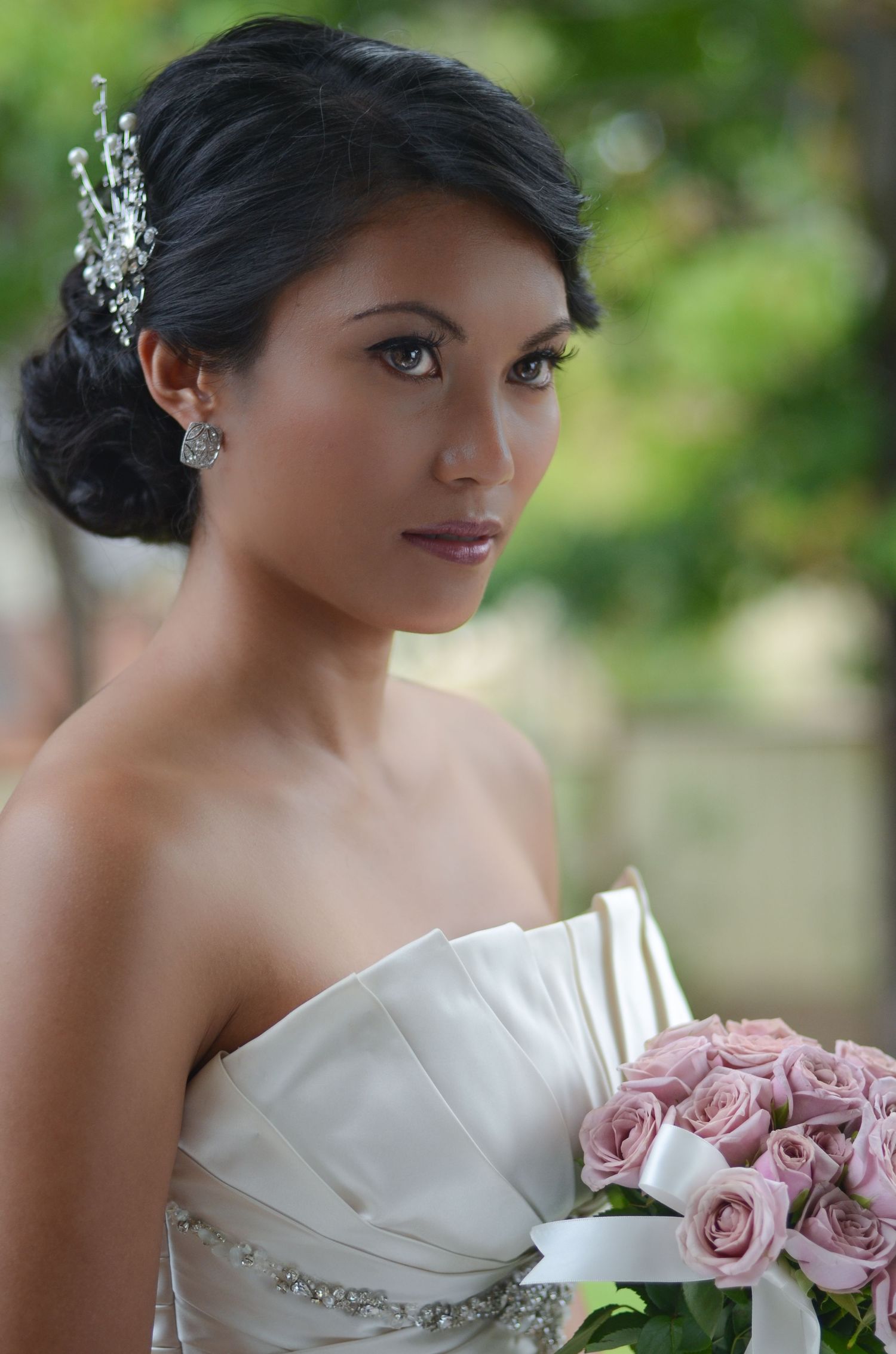 Elegant bridal portrait with crystal hair accessory and pink rose bouquet.