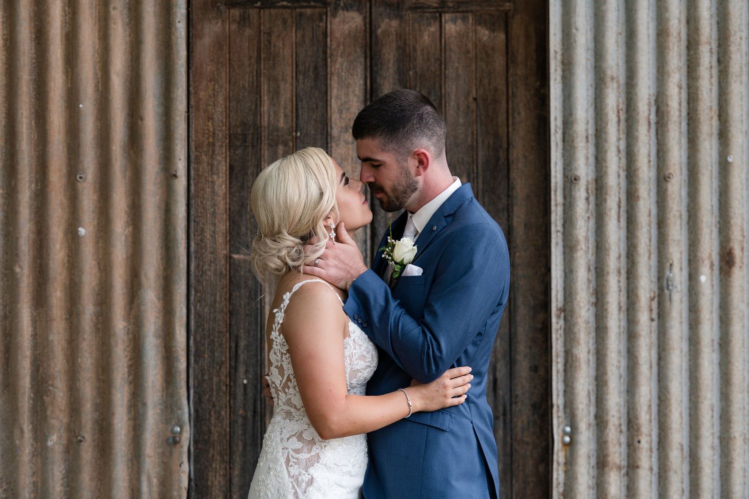 A romantic moment between newlyweds against a rustic wooden door backdrop.